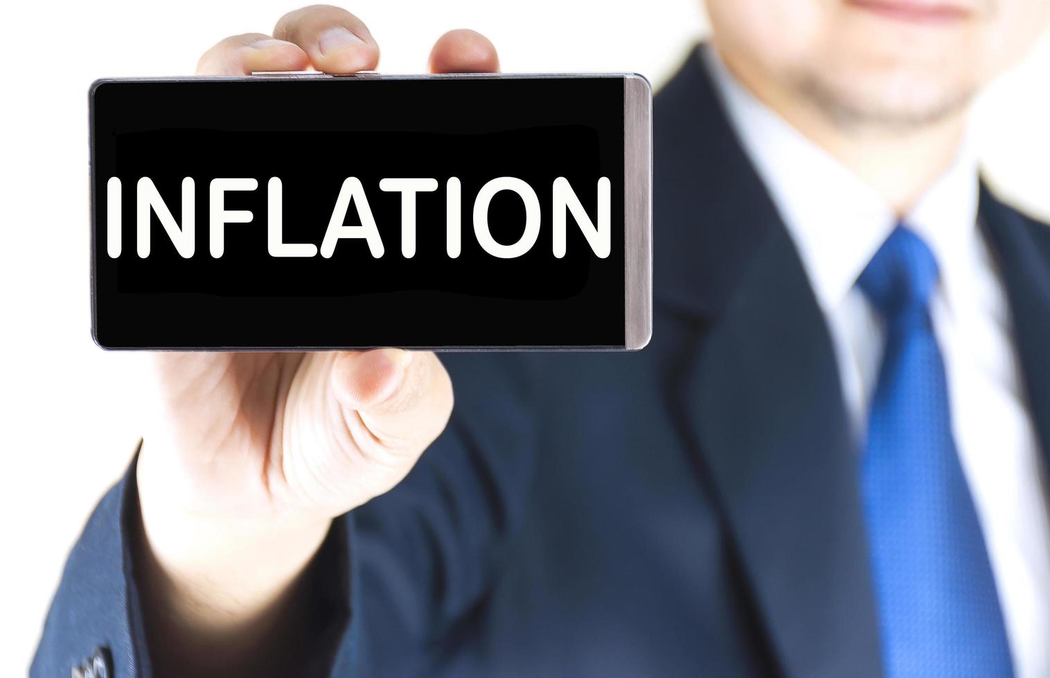 INFLATION word on mobile phone screen in blurred young businessman hand over white background, business concept photo