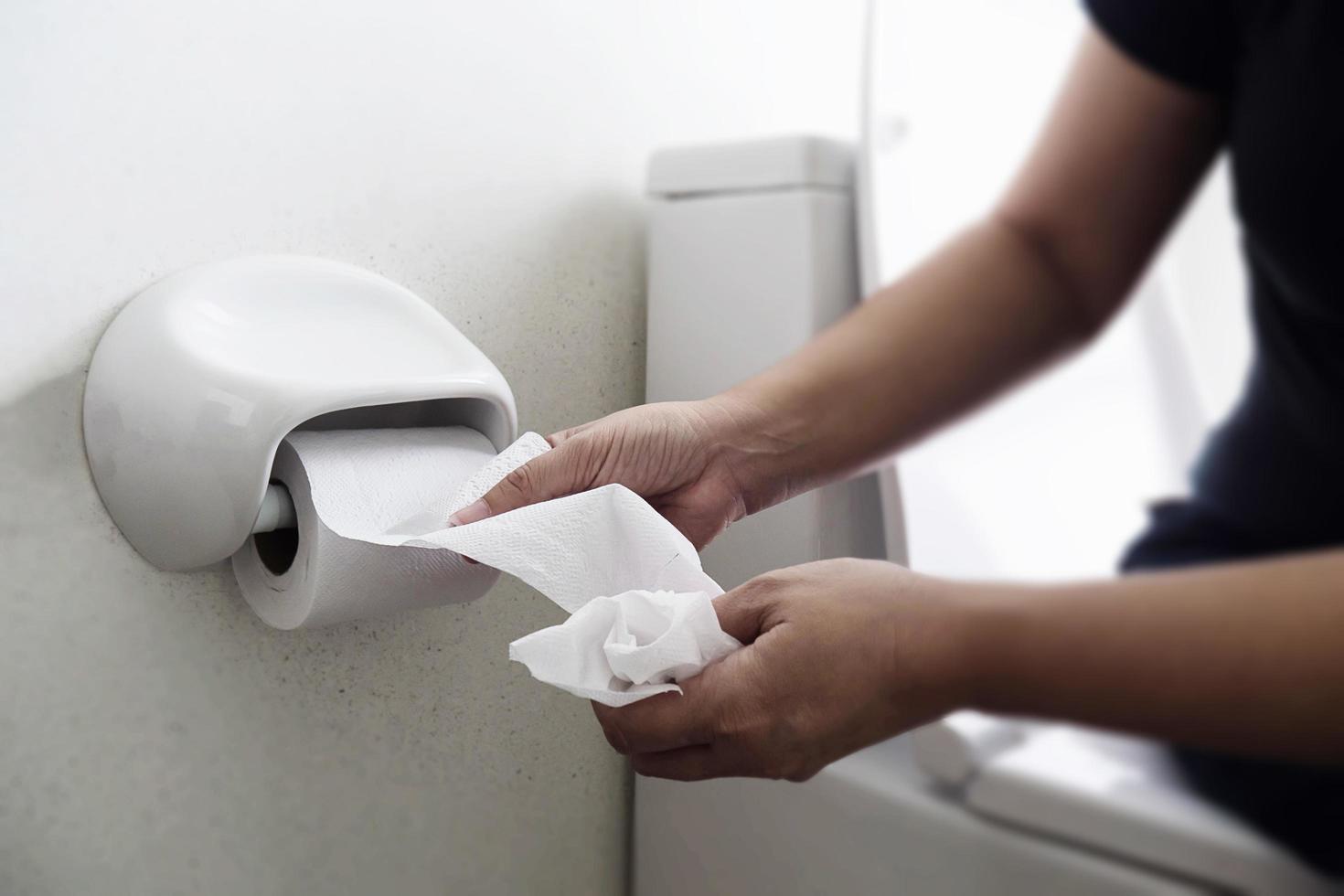 Woman sitting on toilet bowl holding tissue paper  - health problem concept photo