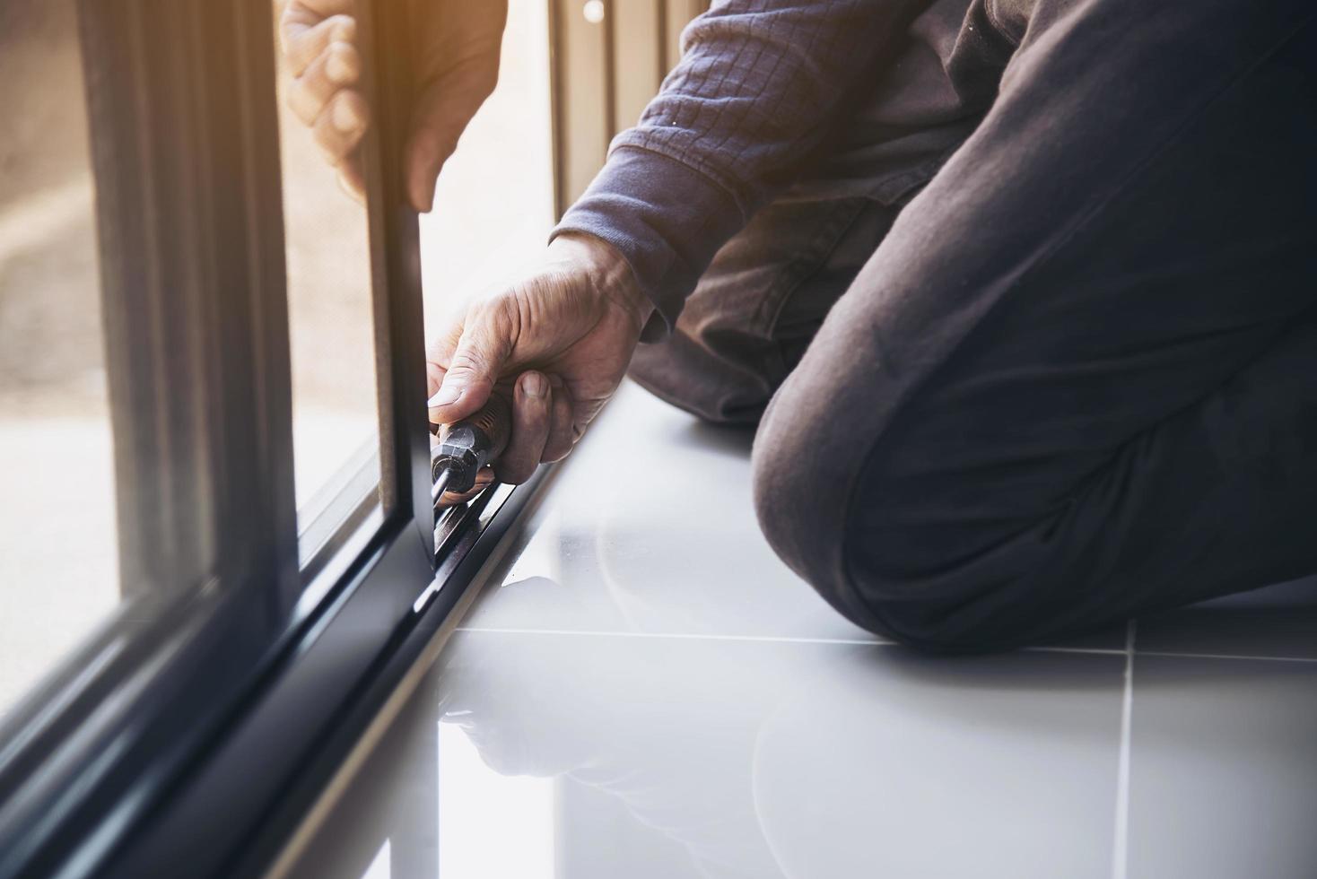 Man doing aluminum frame with glasses and wire screen door and window installation work in construction site photo