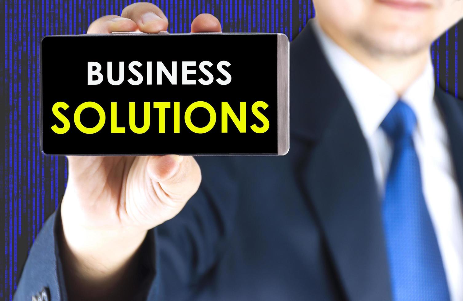 Focused of business solutions word on mobile phone screen in blurred young businessman hand and digital technology background photo