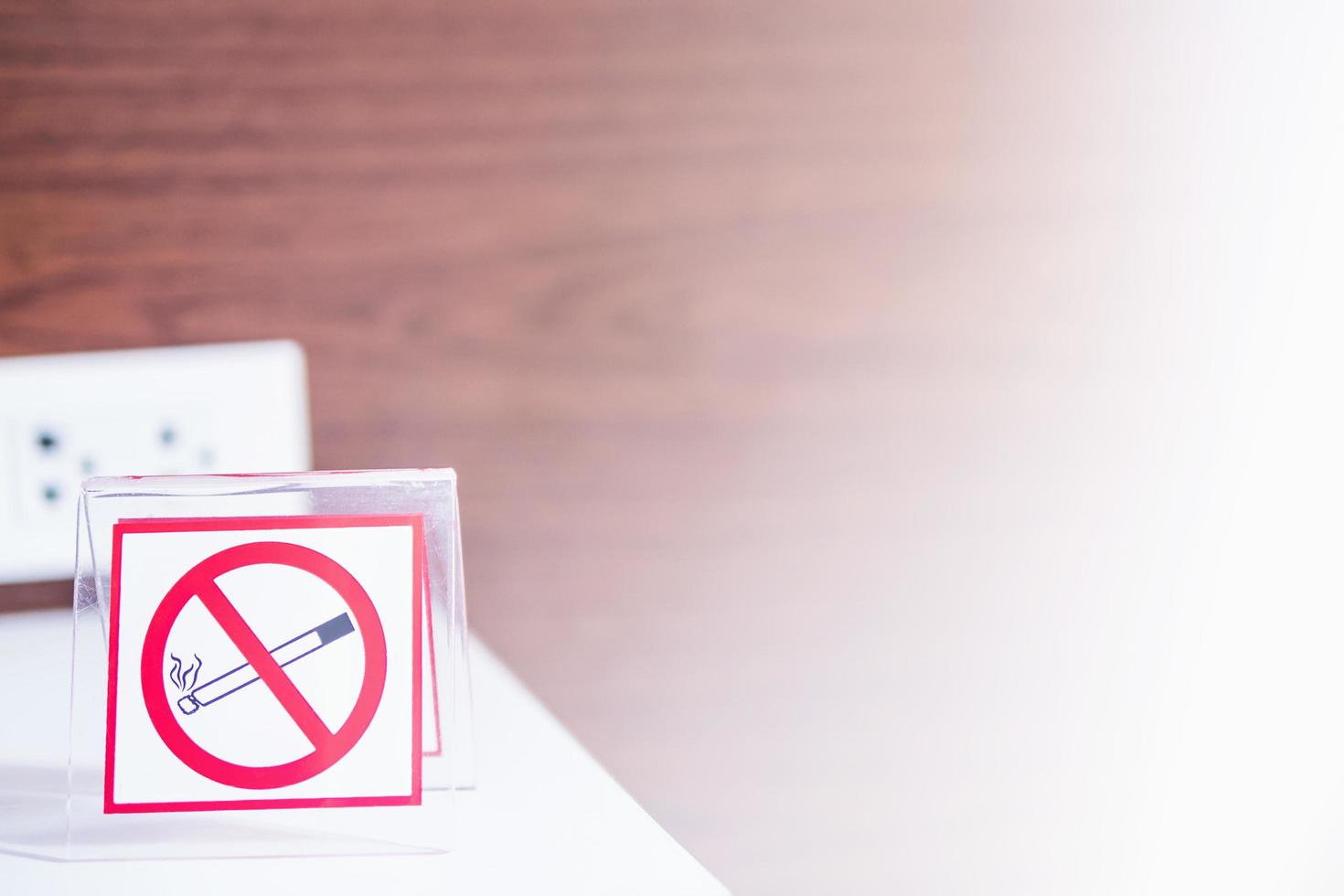 señal de prohibido fumar con fondo de textura de pared de madera y luz blanca que brilla desde el lado derecho foto