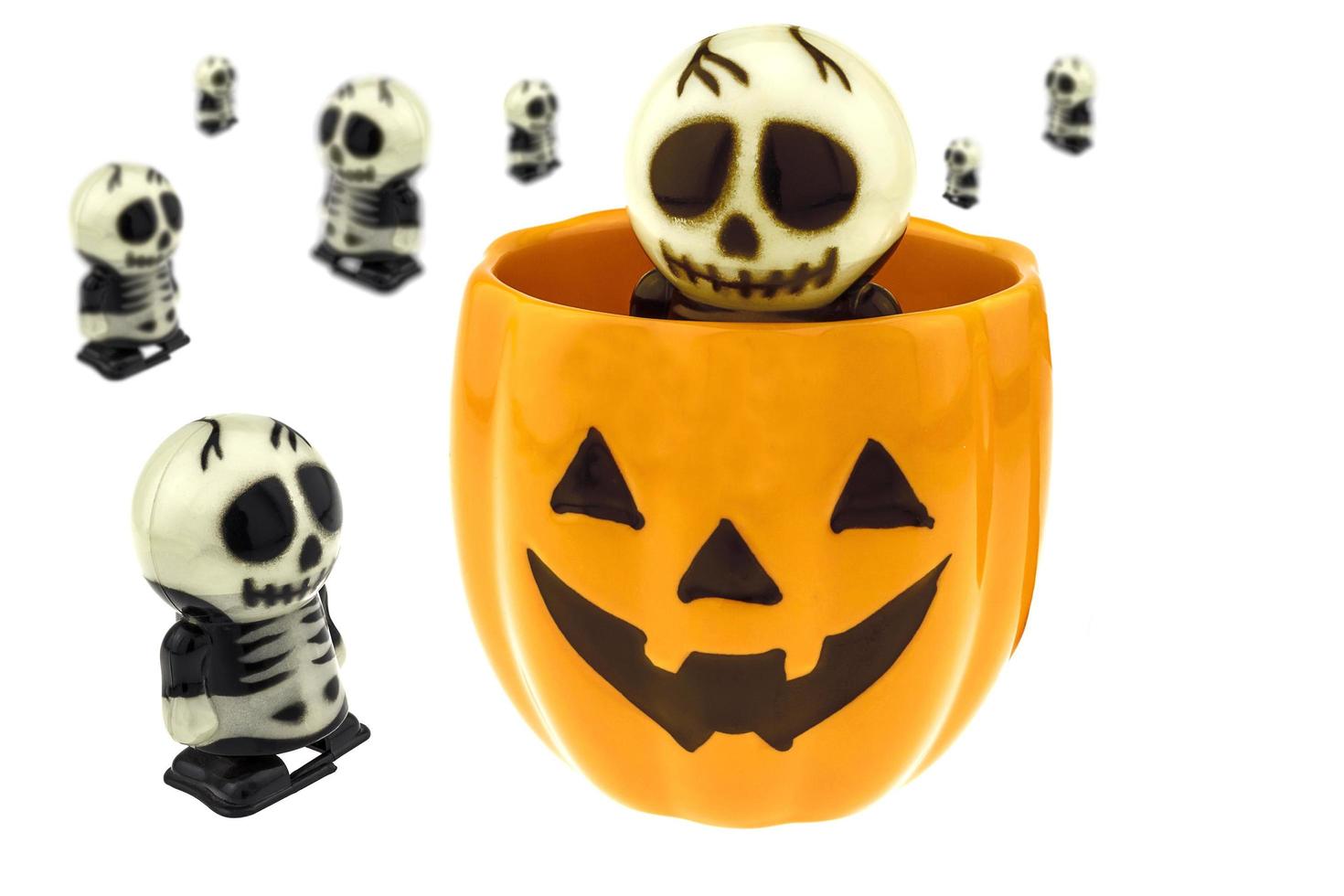 esqueleto de juguete y taza de jack-o-lantern para la decoración de halloween aislada sobre blanco foto