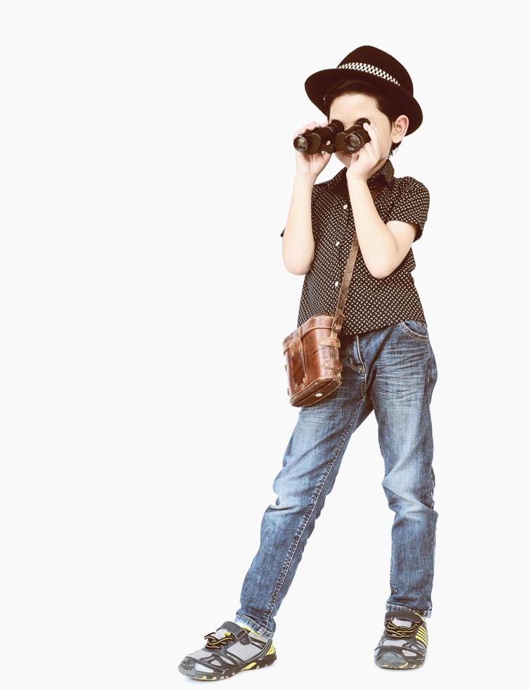 7 years old Asian traveler boy is standing and using binoculars in vintage color style photo