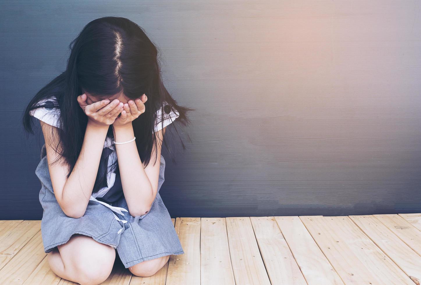 Sad Asian girl sitting on white wood floor photo