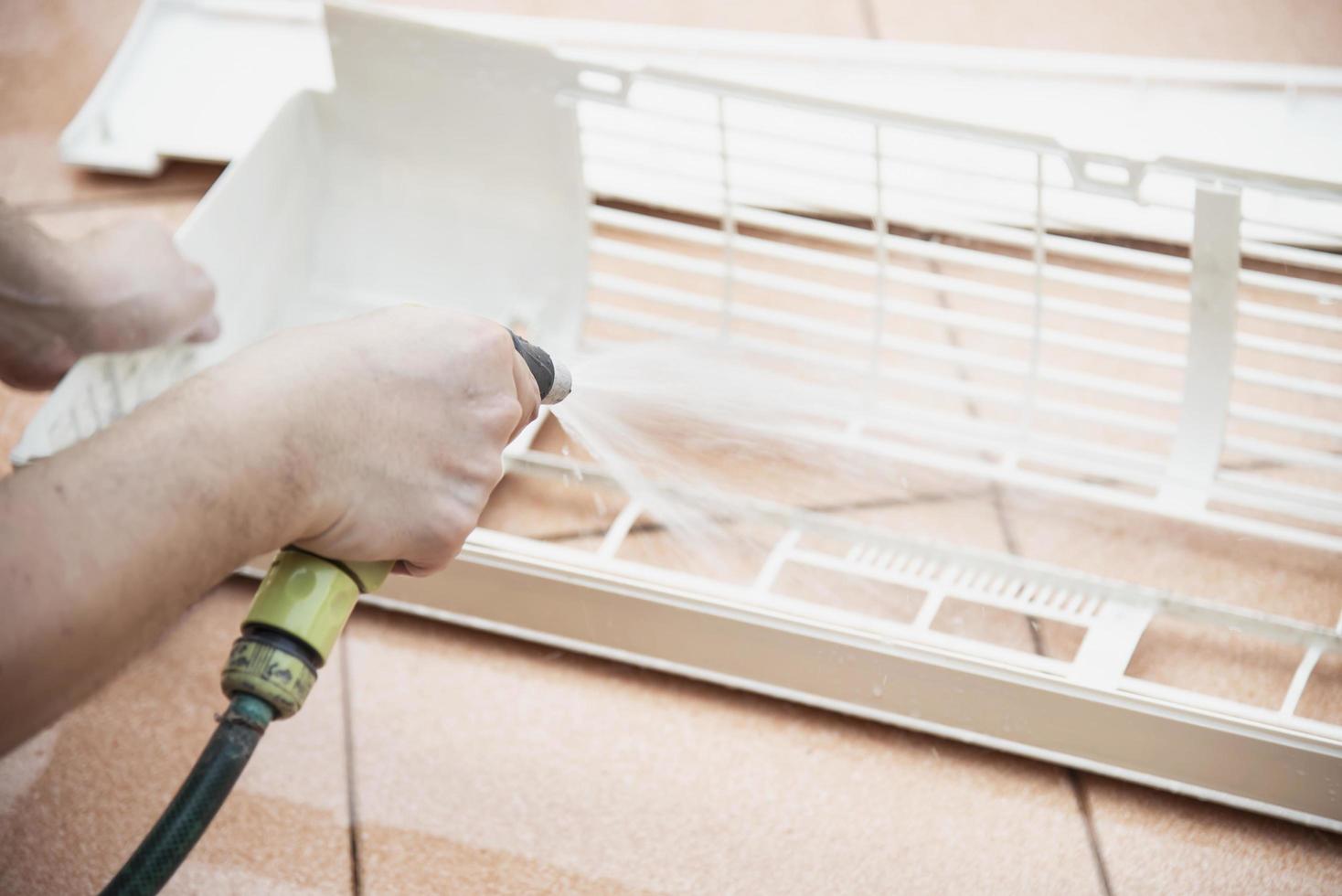 Air conditioner maintenance man cleaning  cover during hot season in Thailand photo