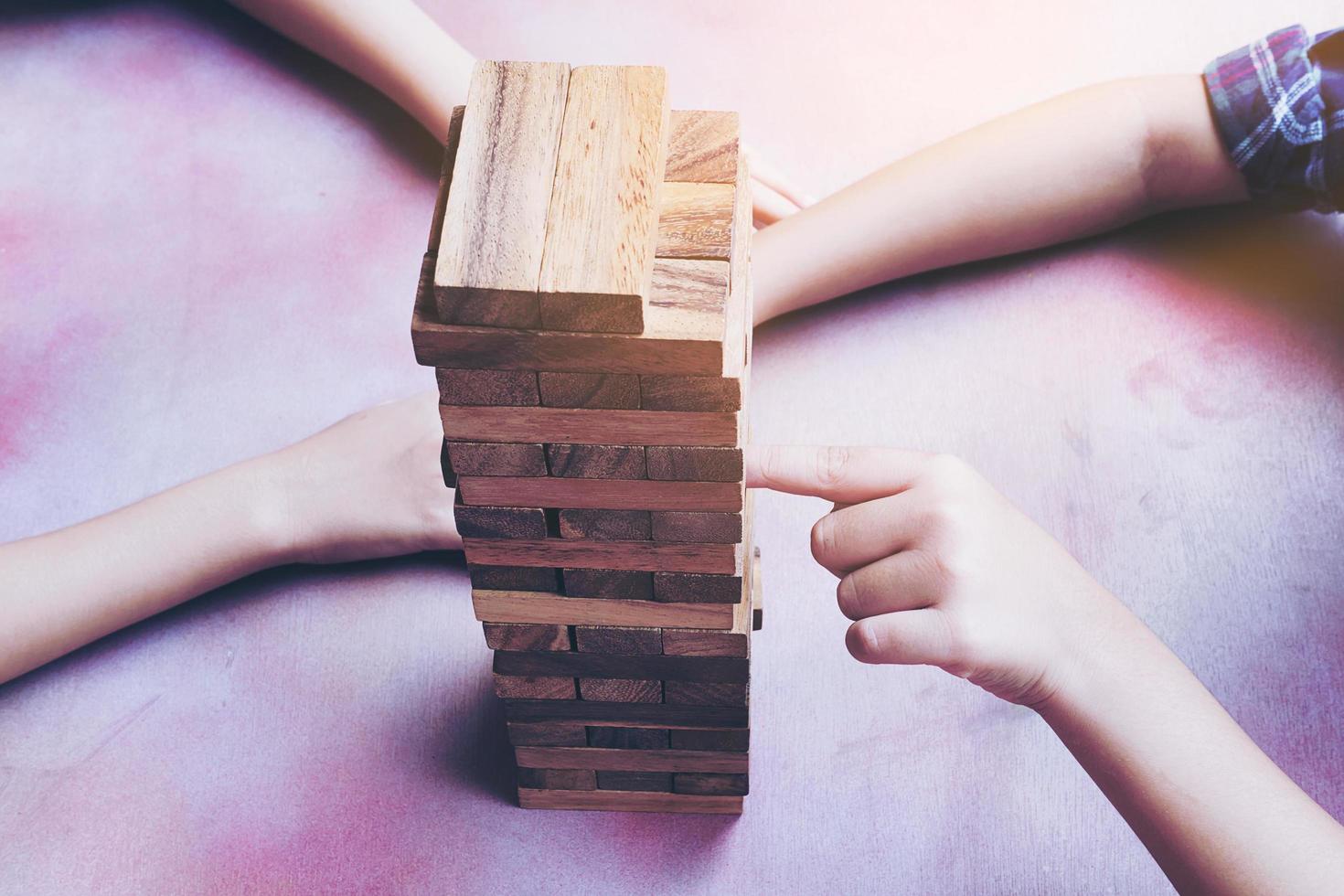 los niños de cerca están jugando al juego de la torre de bloques de madera foto