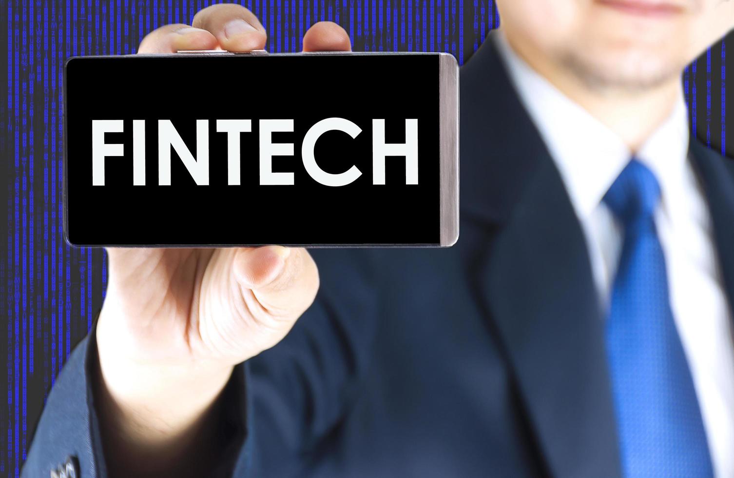 Focused of fintech word on mobile phone screen in blurred young businessman hand and digital technology background photo