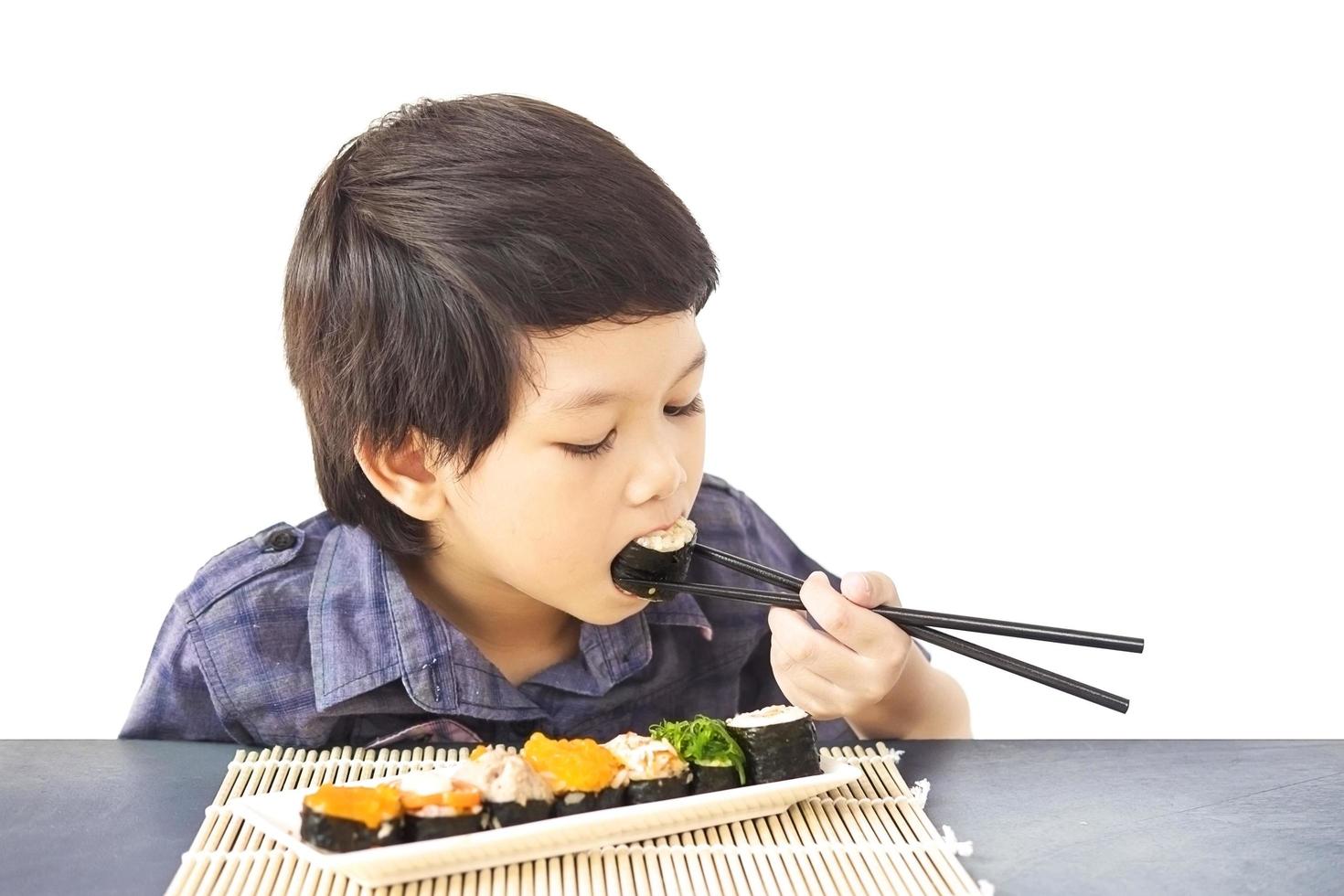 Chico encantador asiático está comiendo sushi aislado sobre fondo blanco. foto