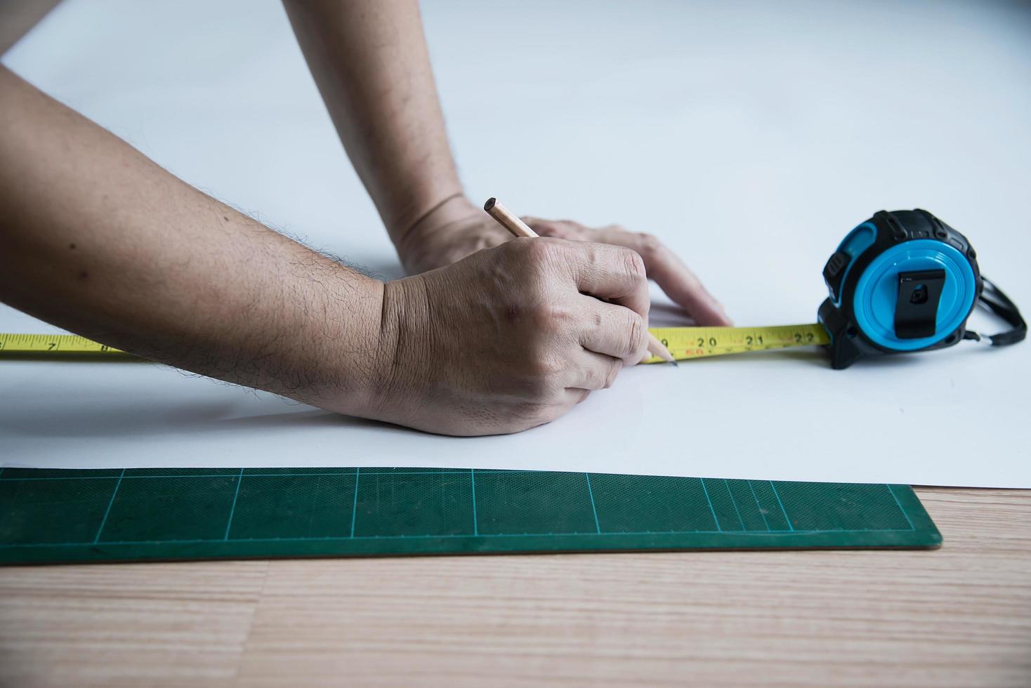 hombre que usa la herramienta de mano de medida haciendo trabajos de corte de papel tapiz en el sitio de construcción de viviendas, personas con el concepto de objeto de herramienta de mano foto