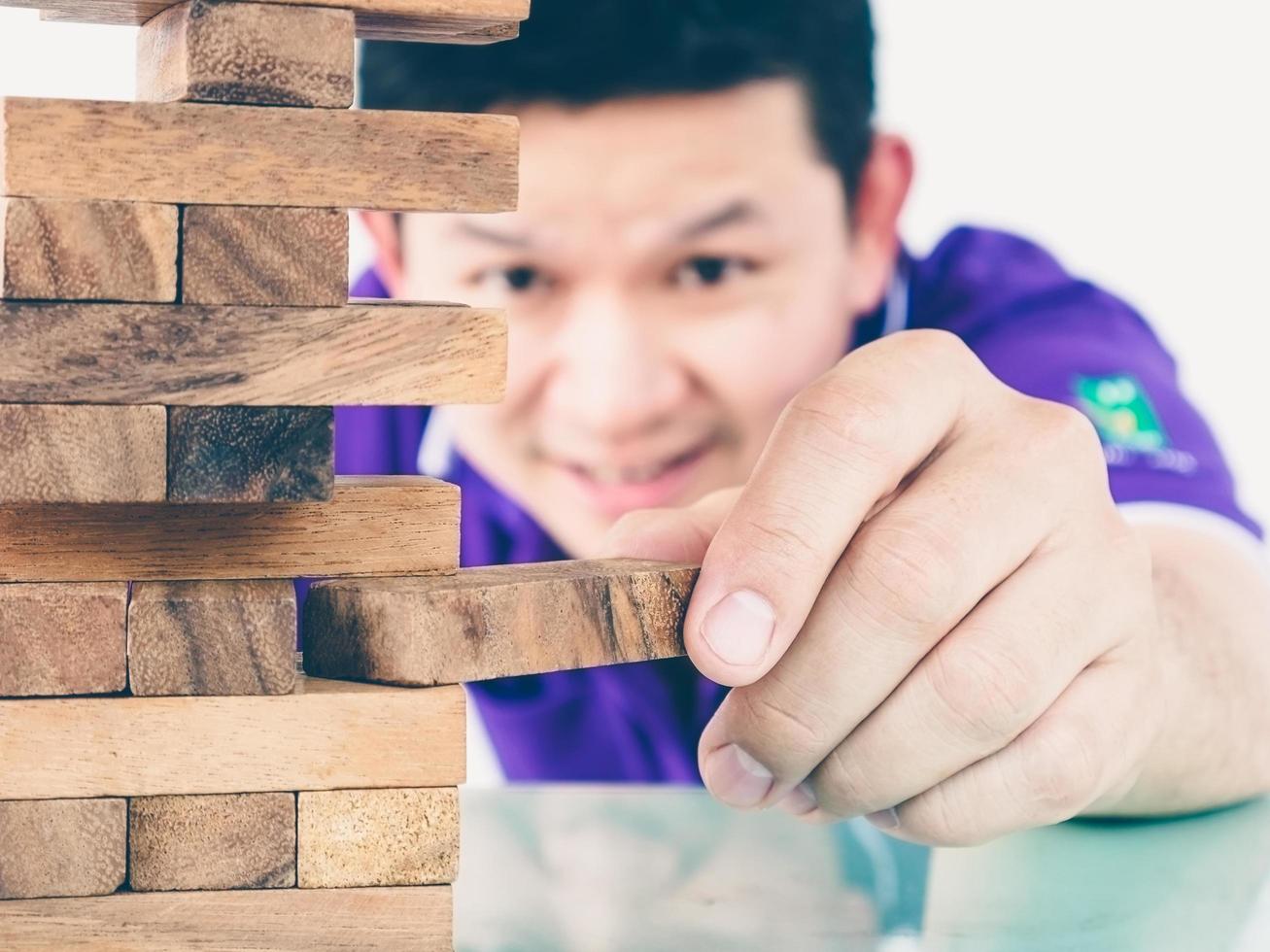 Vintage tone of asian guy is playing a wood blocks tower game for practicing physical and mental skill photo