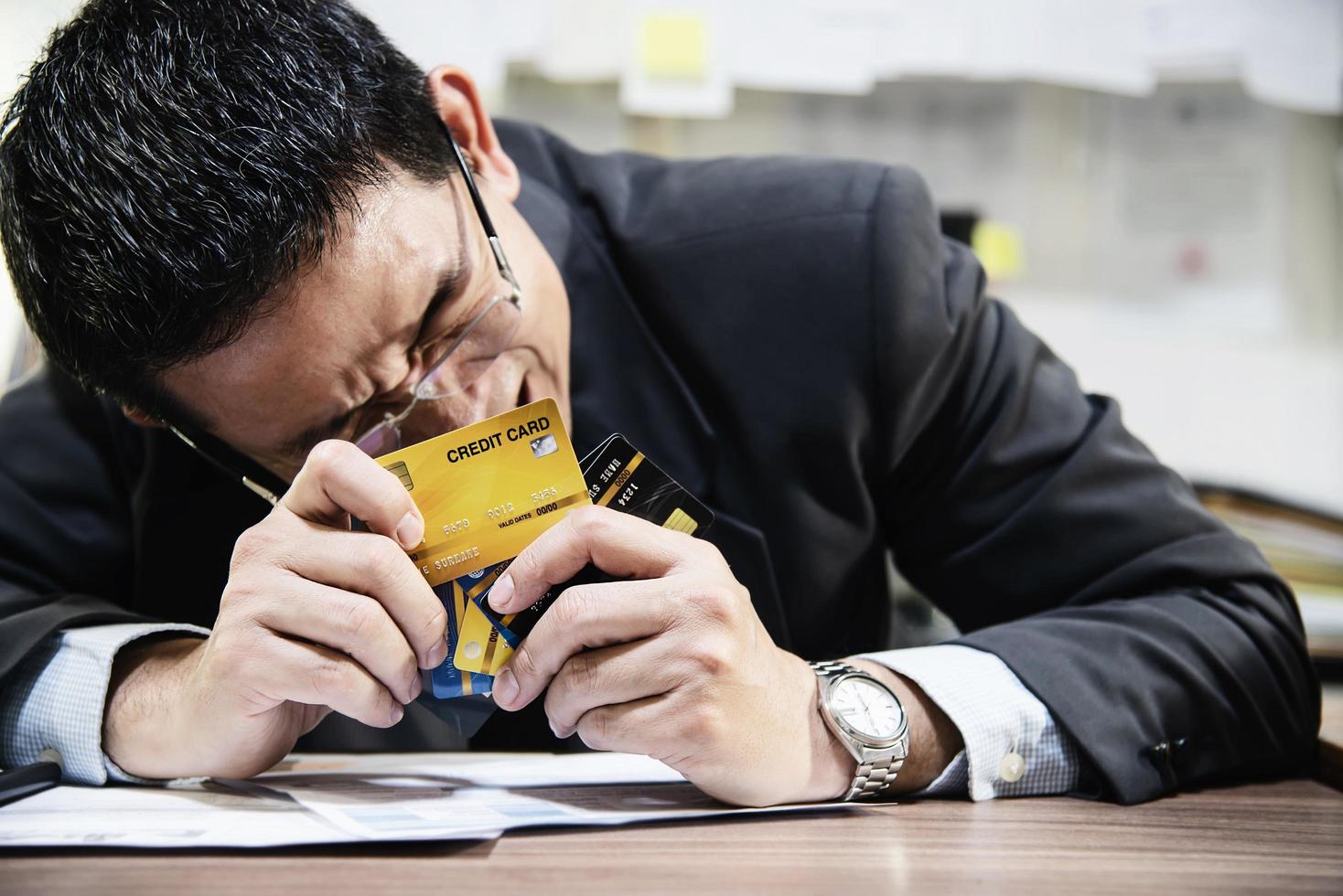 Businessman holding credit cards thinking seriously about payment loan problem - people with personal financial crisis concept photo