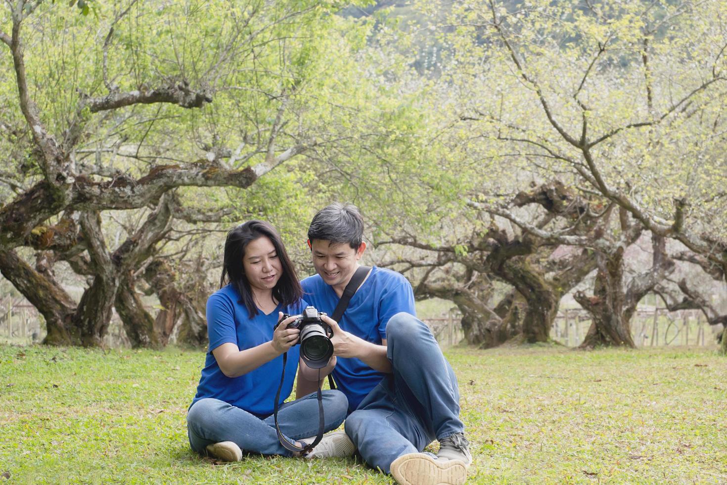 Asian couple happy taking photo in beauliful nature peach garden in Doi Ang Khang, Chiangmai Thailand