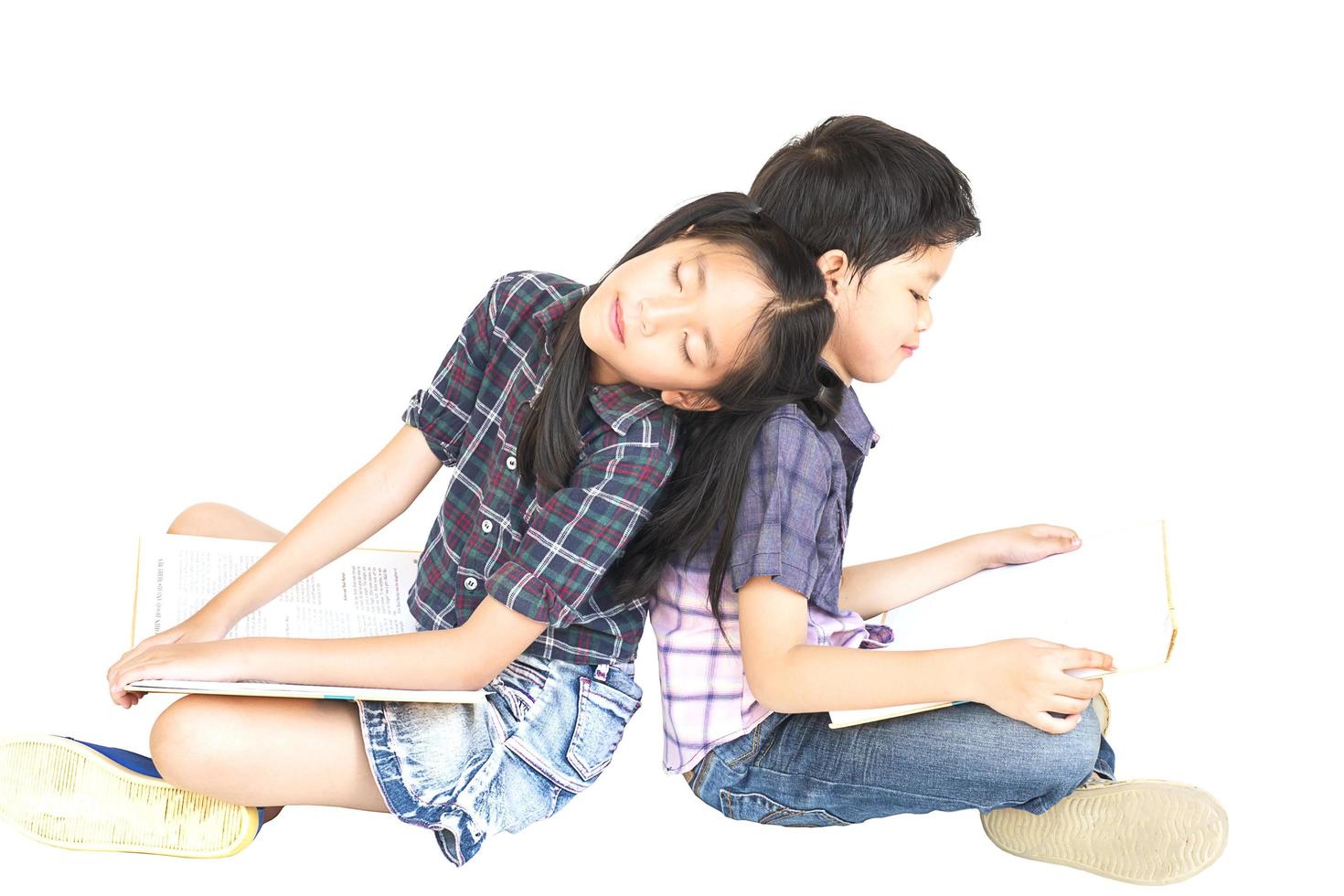 10 and 7 years Asian school girl and boy sitting sleeping reading book together isolated over white photo