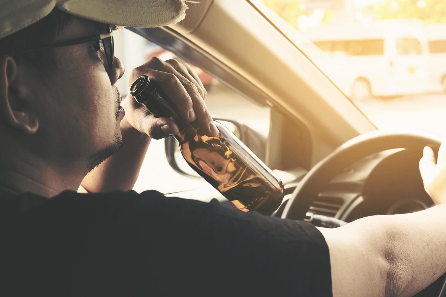 Man drinking beer while driving a car photo