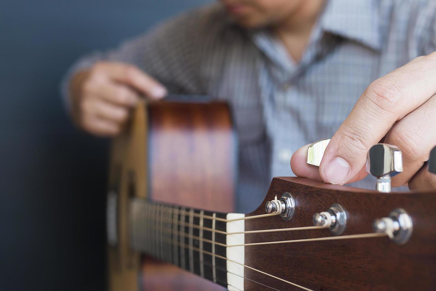 Man tuning acoustic guitar photo