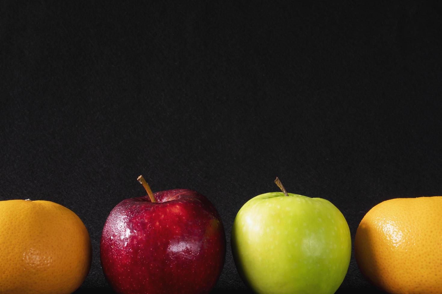 Fresh red green apple and orange over gray black background - fresh fruit background concept photo