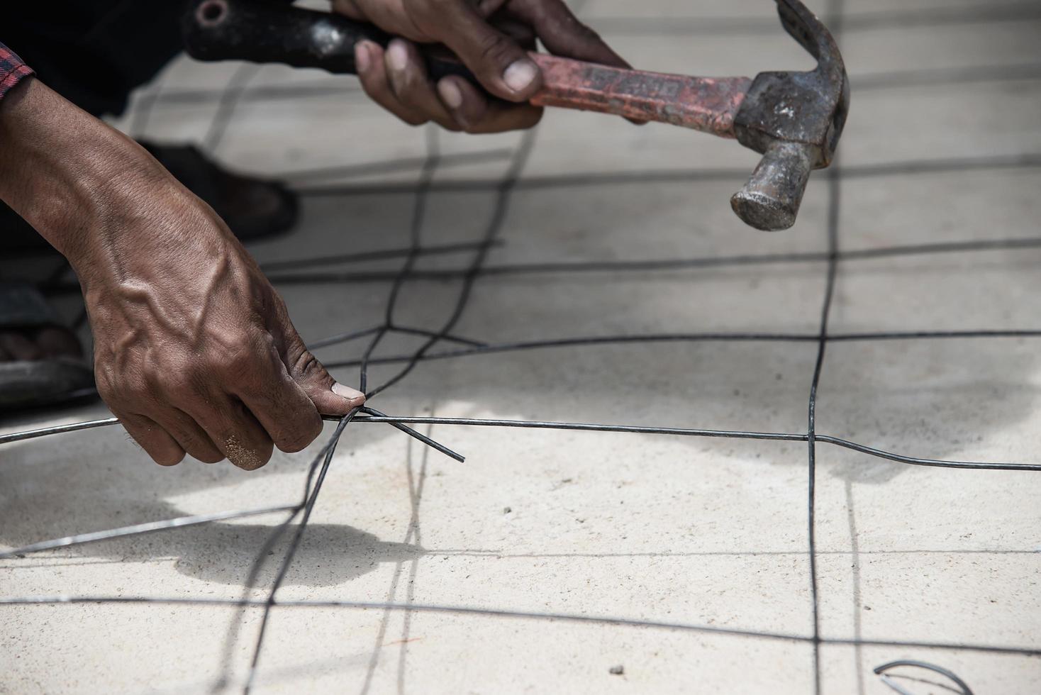 trabajador de la construcción está atando el acero estructural, preparación de vertido de hormigón del suelo foto