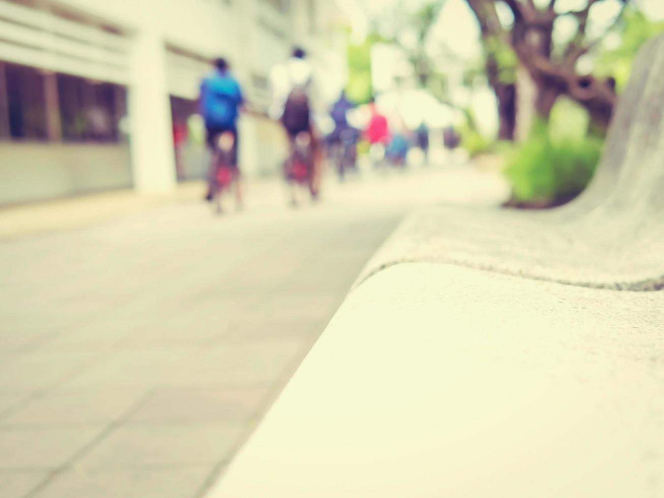Vintage style photo of bench sitting with blurred bicycling student in the campus