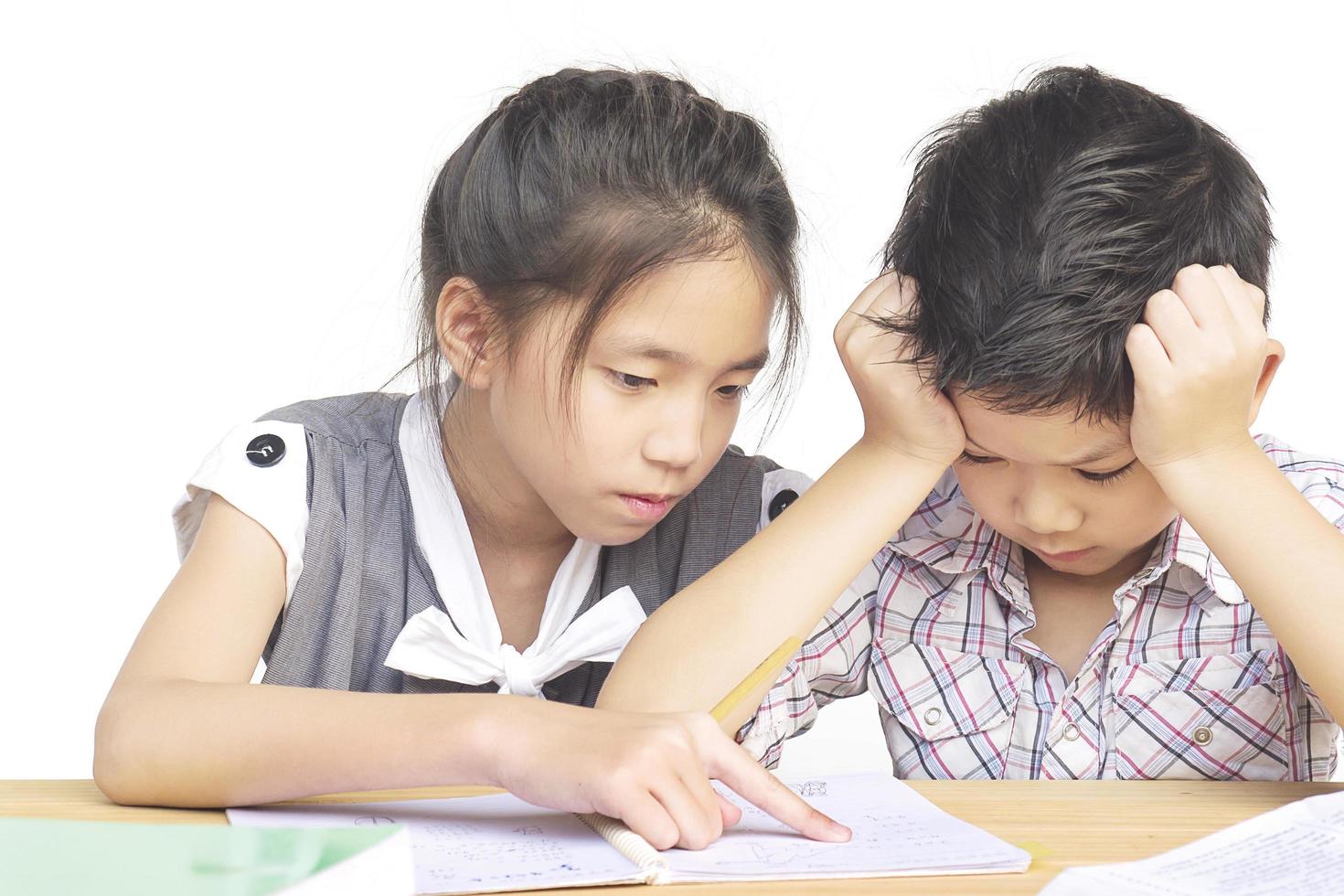 Sister try to teach her naughty younger brother to do homework  isolated over white background photo