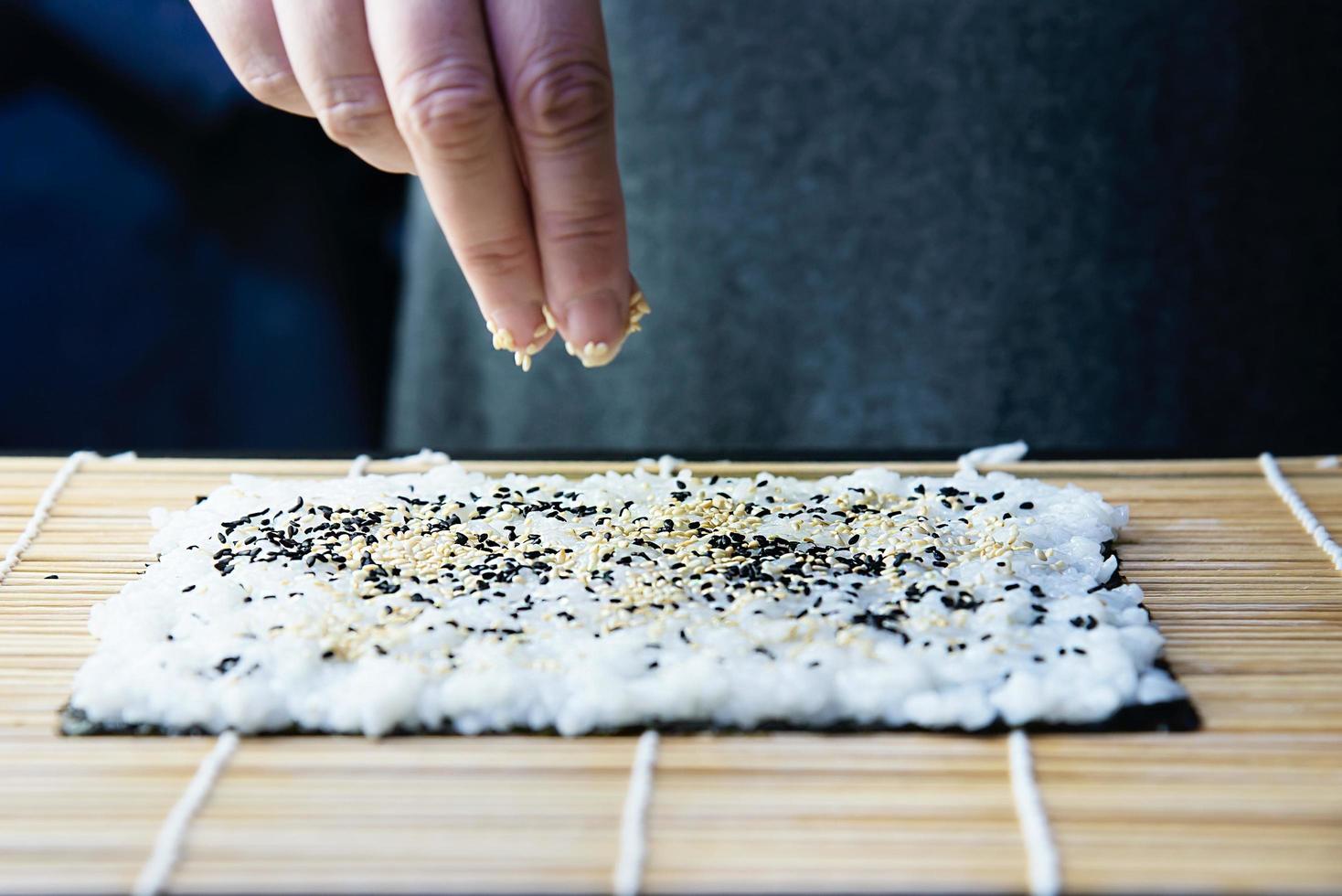 Chef preparando rollo de sushi sobre fondo de mesa negra - gente con plato favorito concepto de comida japonesa foto