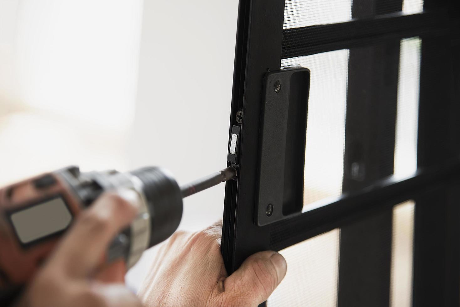 Man doing aluminum frame with glasses and wire screen door and window installation work in construction site photo