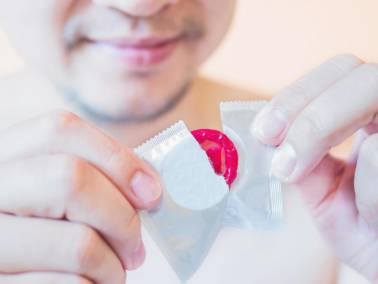 Man is tearing red condom package safe sex concept photo