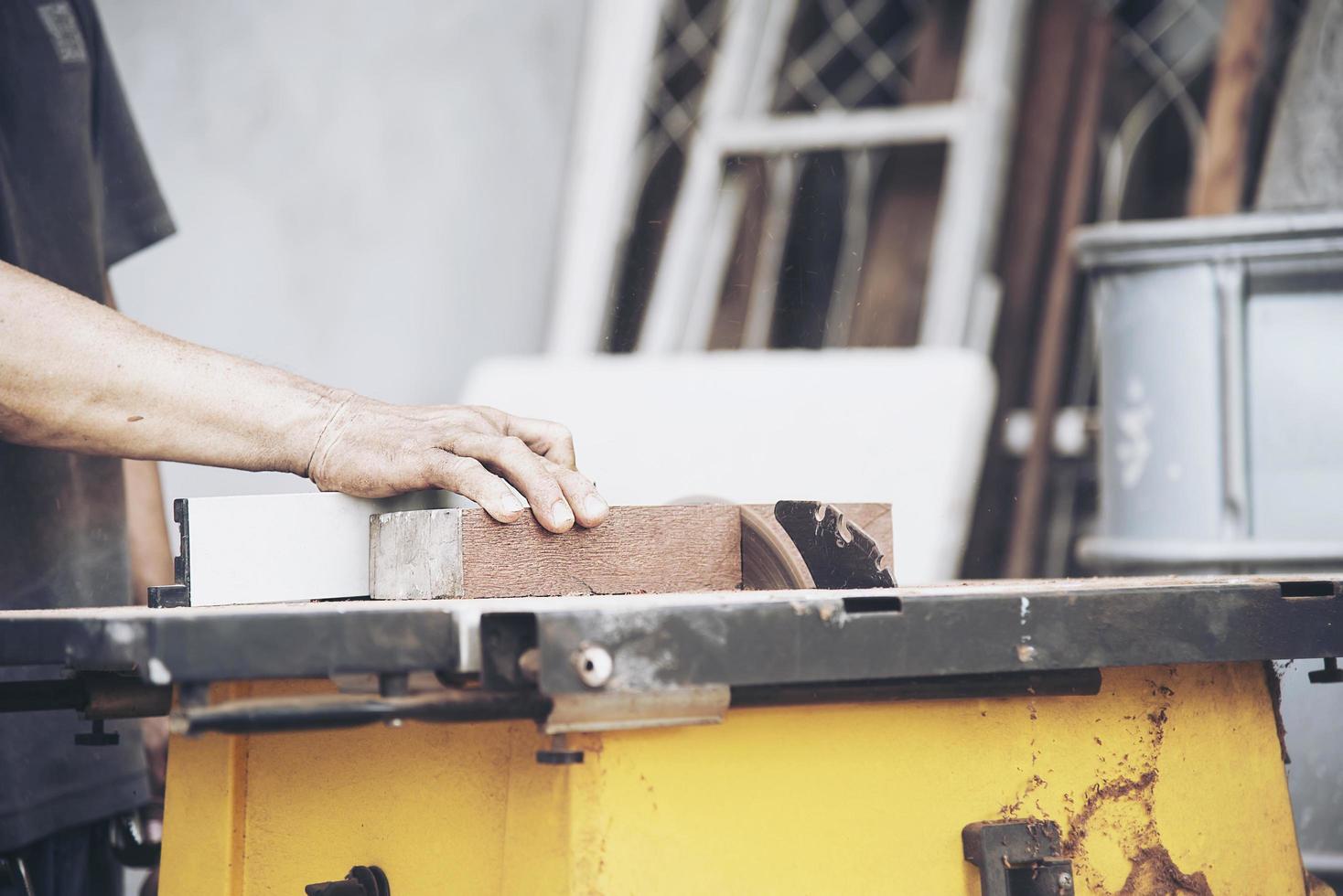 Carpenter man is working with circular saw machine table tool for cutting his wooden piece work photo