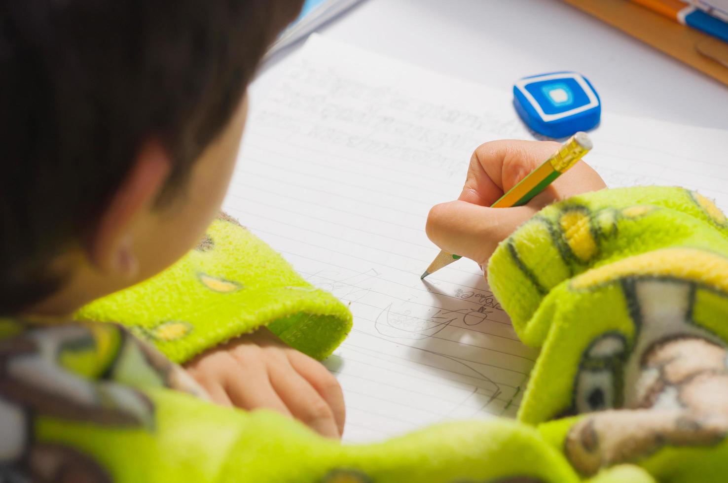 A boy is doing his homework, writing a book photo
