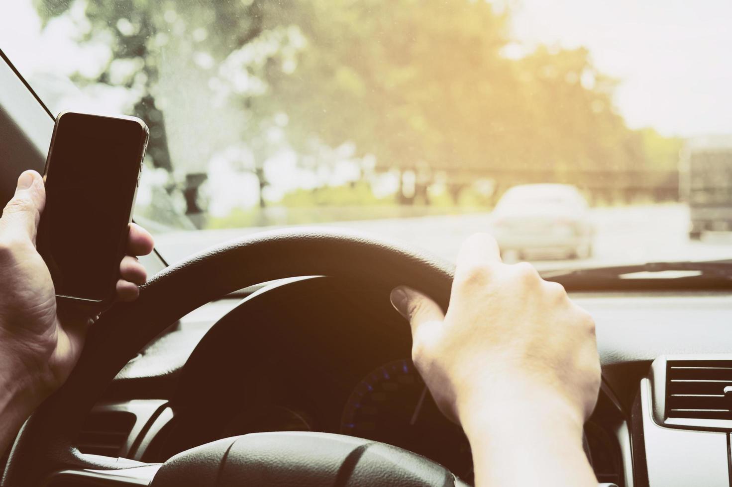 Close up of a man driving car dangerously while using mobile phone photo