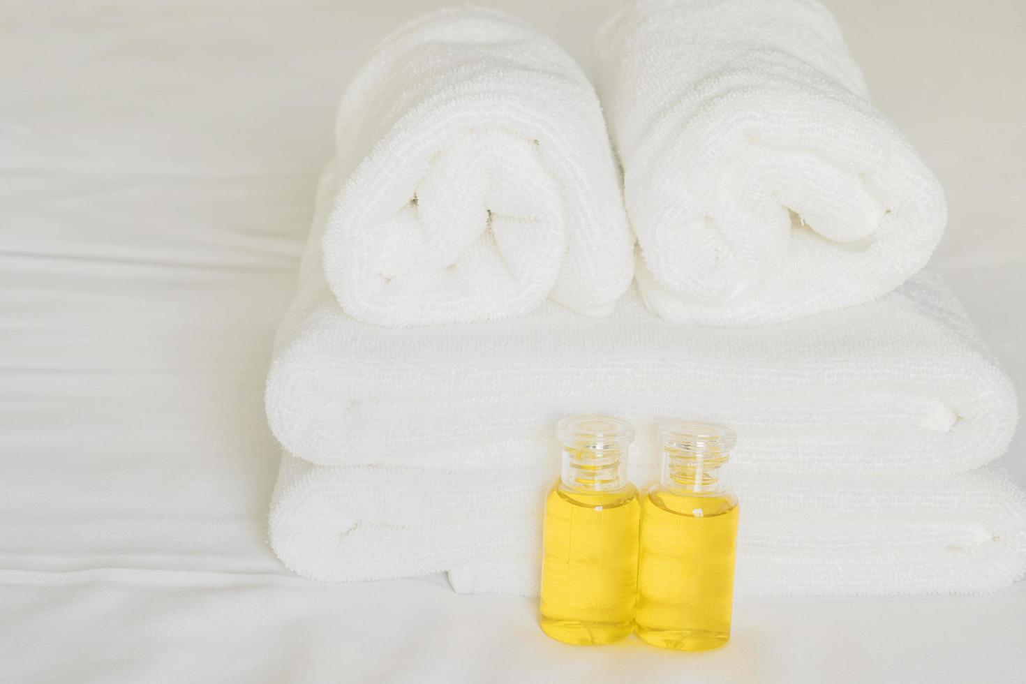 Hotel towel with shampoo and soap bottle set on white bed photo