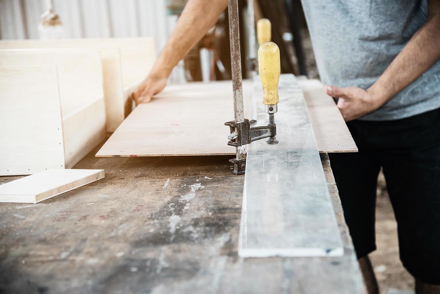 Carpenter working with wood furniture product preparation using hand tools and machine table station photo