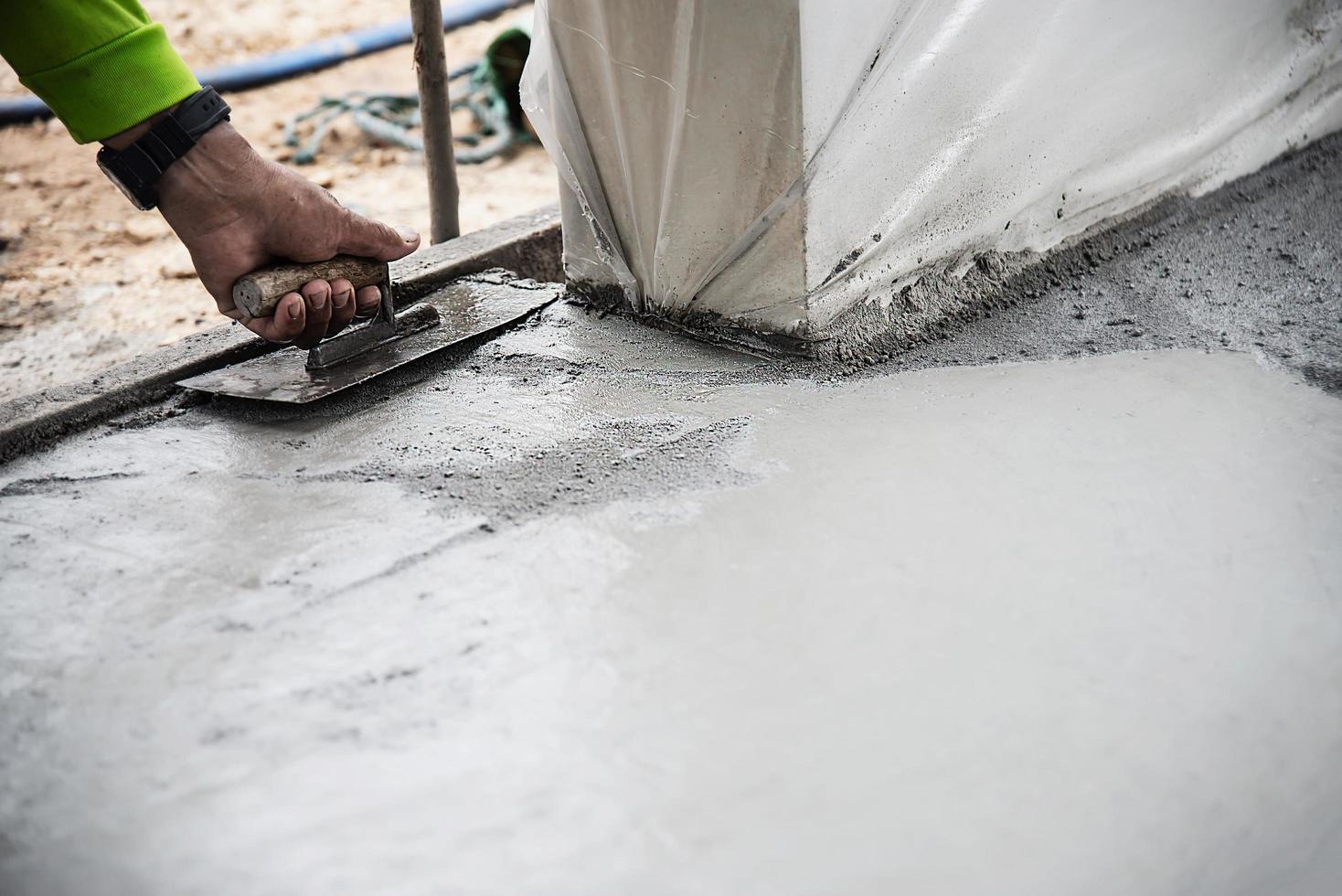 Workman doing road surface concrete pouring job in construction site photo