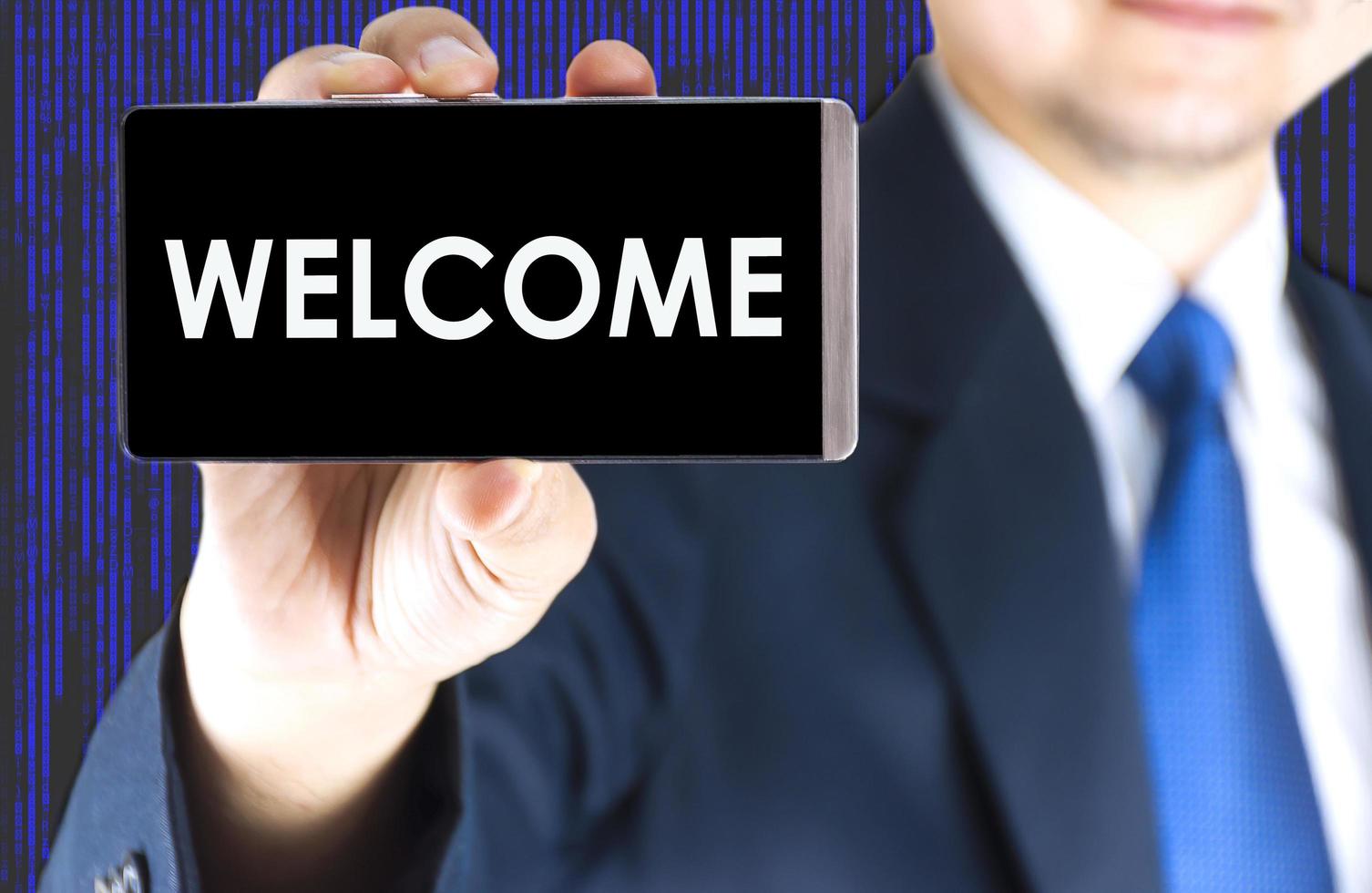 WELCOME word on mobile phone screen in blurred young businessman hand and digital technology background, business concept photo