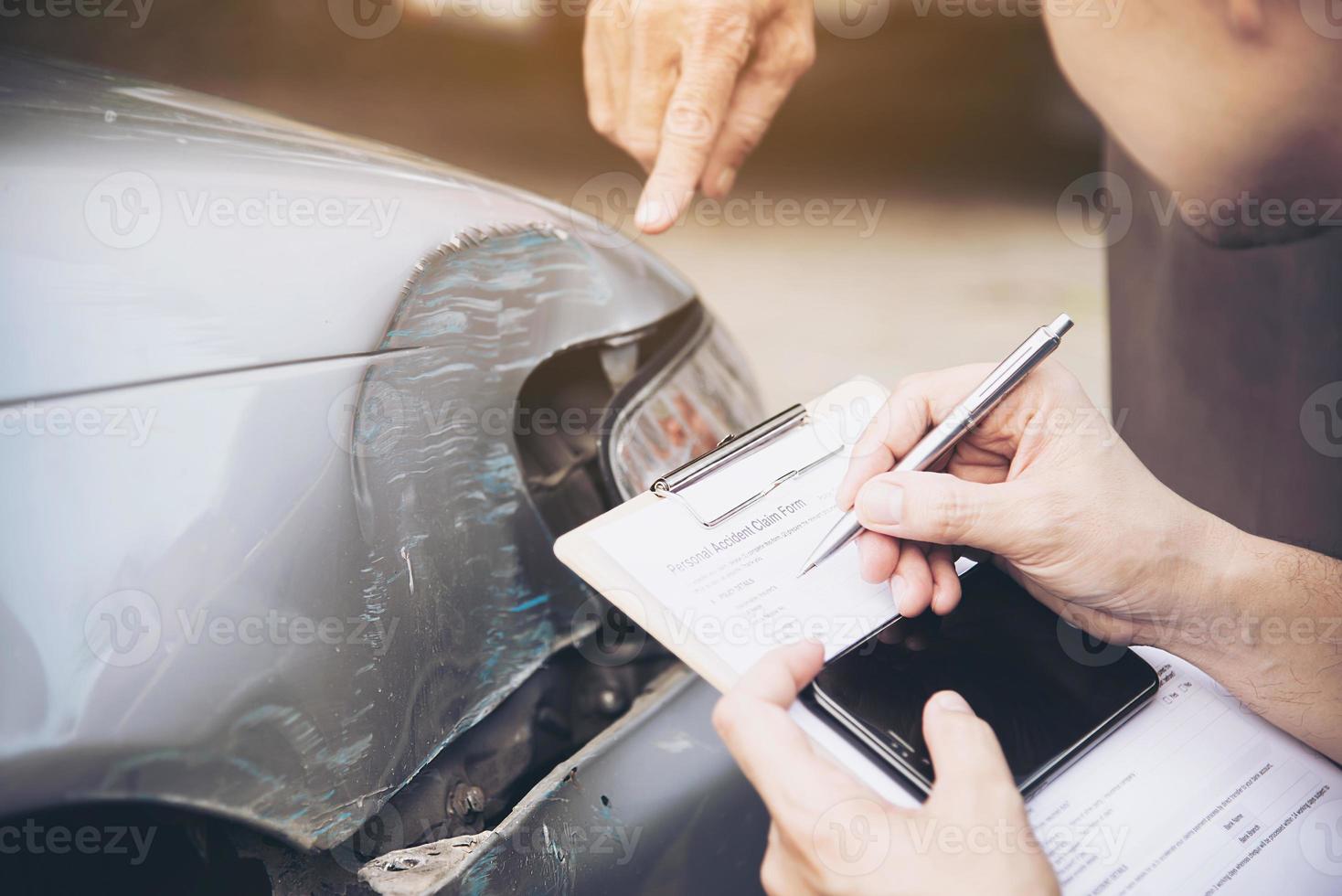 agente de seguros que trabaja durante el proceso de reclamación de accidentes de coche en el lugar - concepto de reclamación de seguros de personas y coches foto