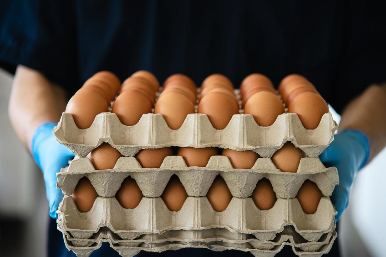 un hombre lleva una bandeja de huevos de 3 capas para mantenerse seguro en casa poniendo guantes sanitarios durante la propagación del virus corona covid-19 - personas que mantienen alimentos en el concepto de período de propagación viral covid-19. foto