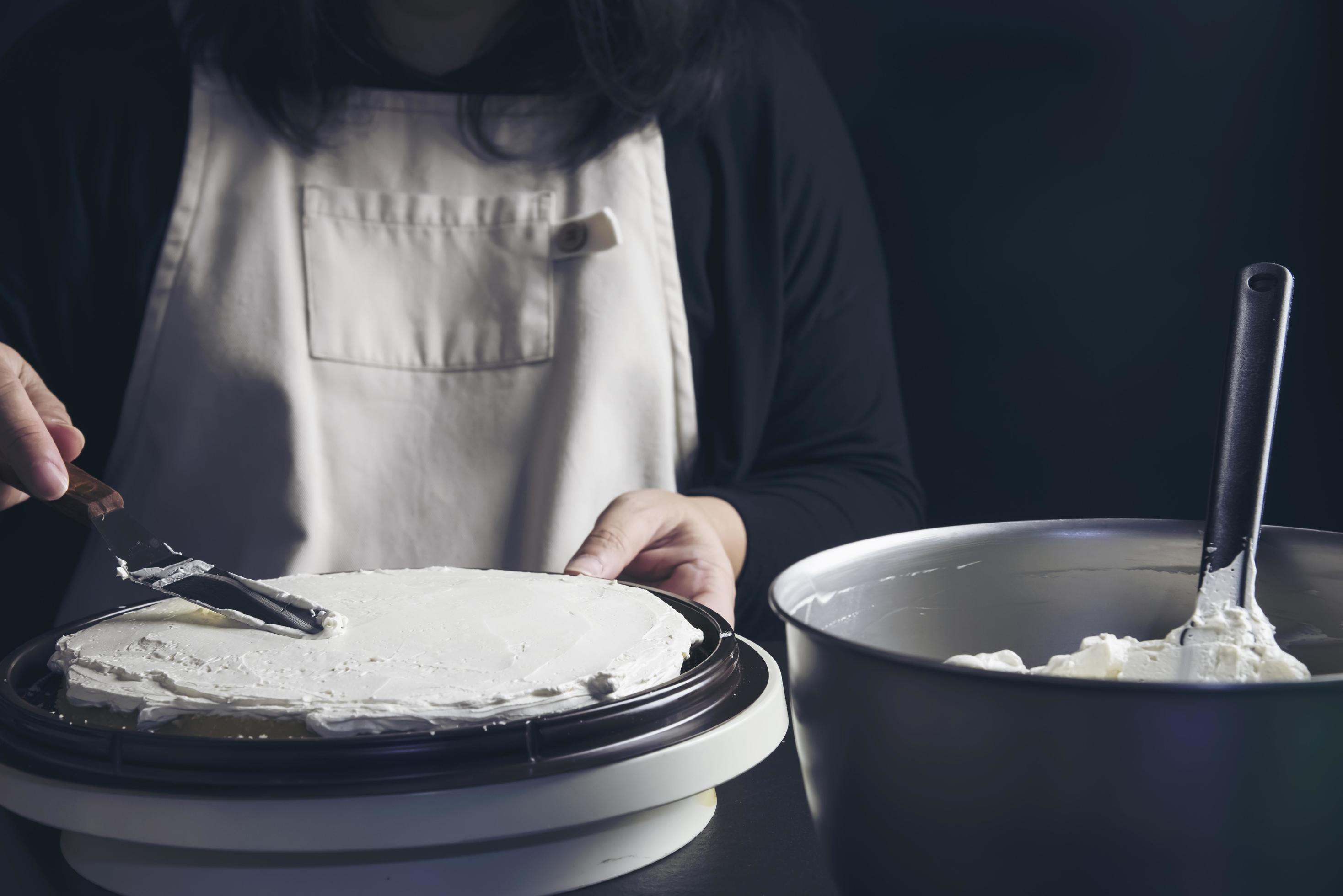 Lady making cake putting cream using spatula homemade bakery cooking