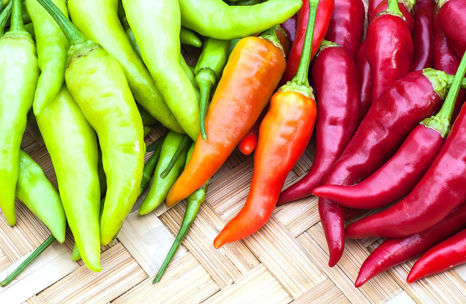 Mixed color chilli on weave bamboo background photo
