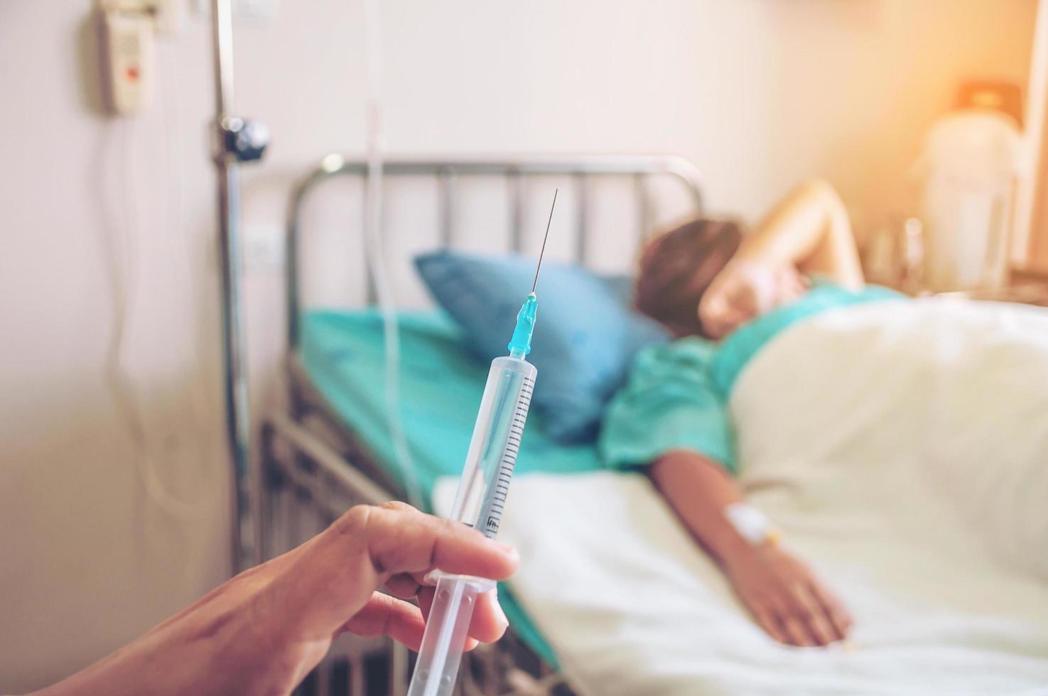 Doctor holding syringe in hand ready for injecting with a patient background in the hospital photo