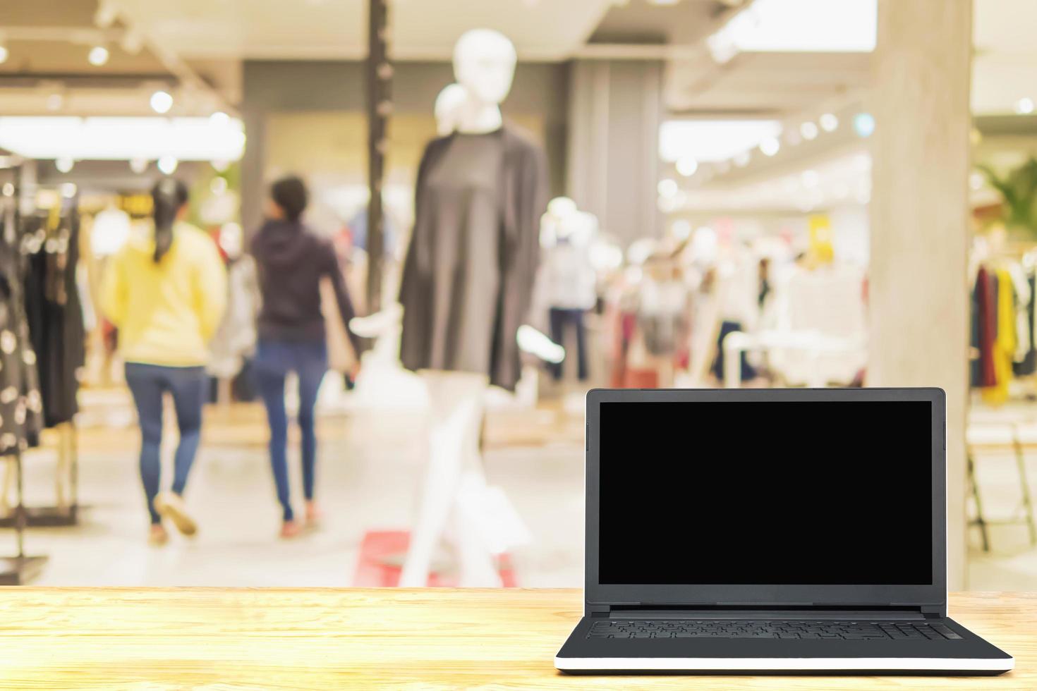 Laptop on wooden table over blurred superstore background photo