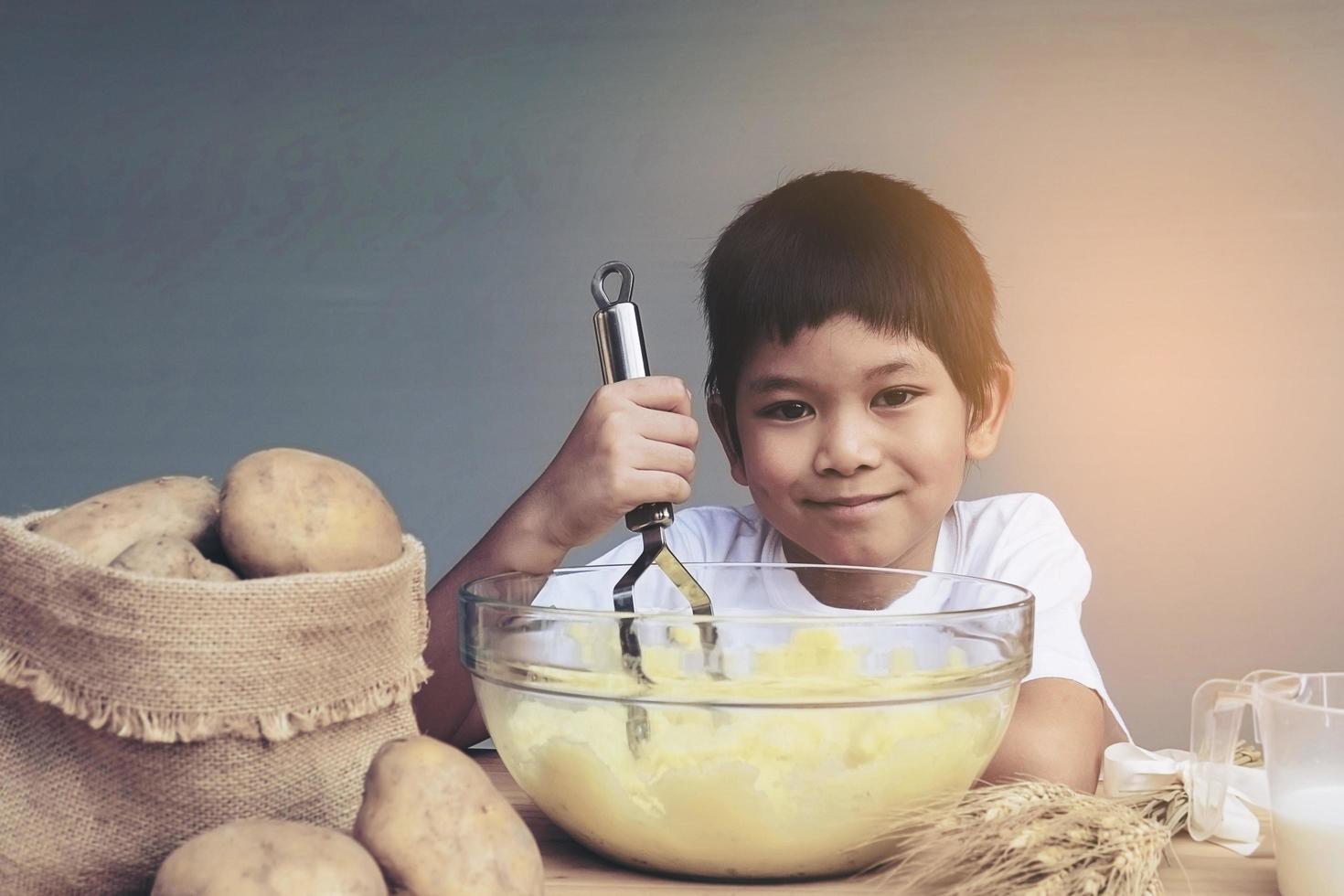 7 years boy making mashed potatoes happily photo