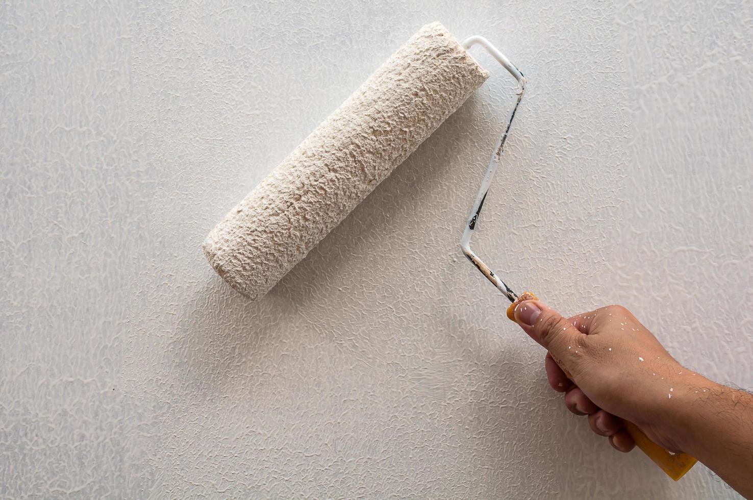Hand holding rolling paint brush, wall painting photo