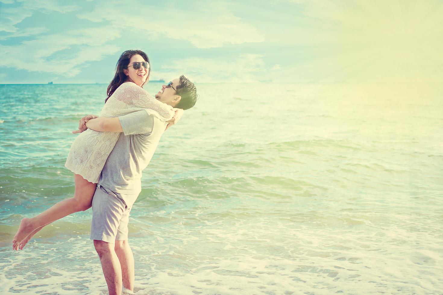 Vintage tone photo of Asian couple on beach with warm sun light from top corner