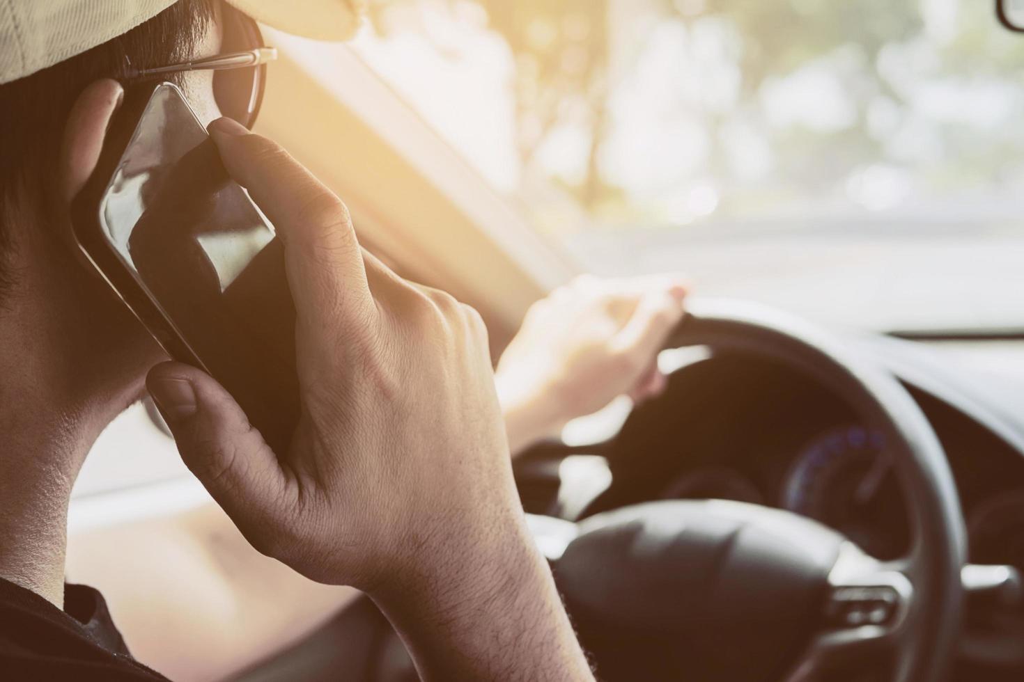 Close up of a man driving car dangerously while using mobile phone photo