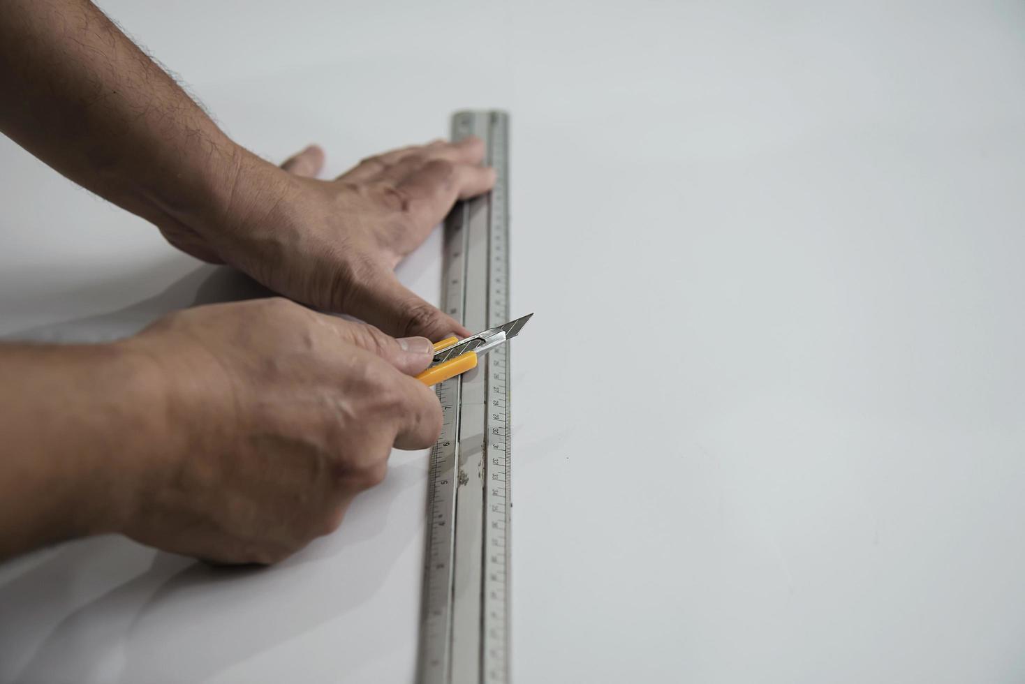 hombre que usa la herramienta de mano de medida haciendo trabajos de corte de papel tapiz en el sitio de construcción de viviendas, personas con el concepto de objeto de herramienta de mano foto