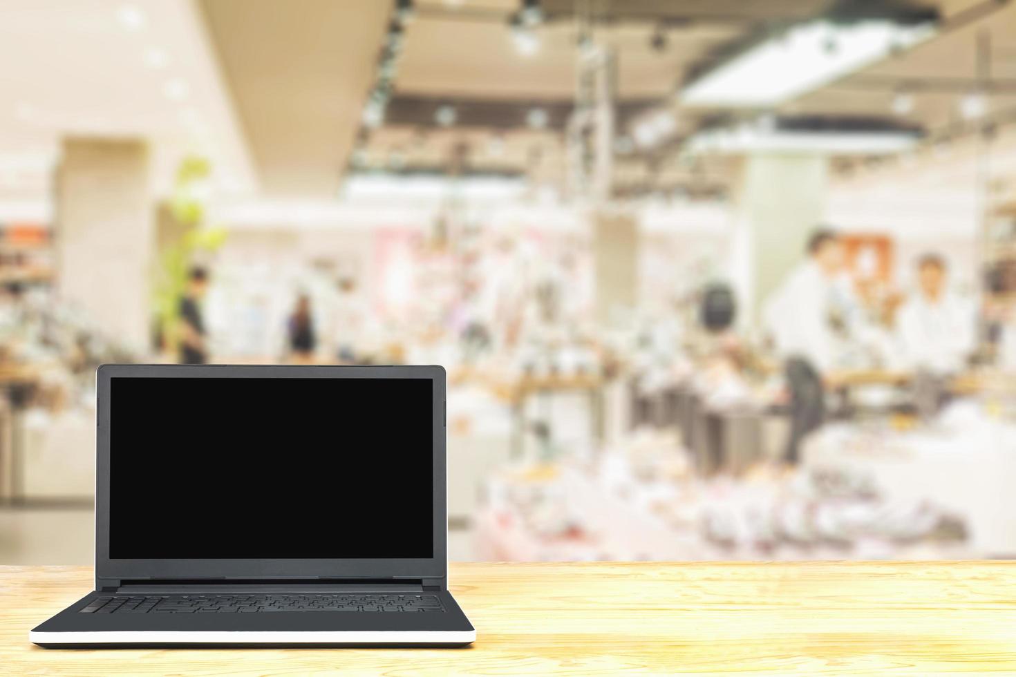 Laptop on wooden table over blurred superstore background photo