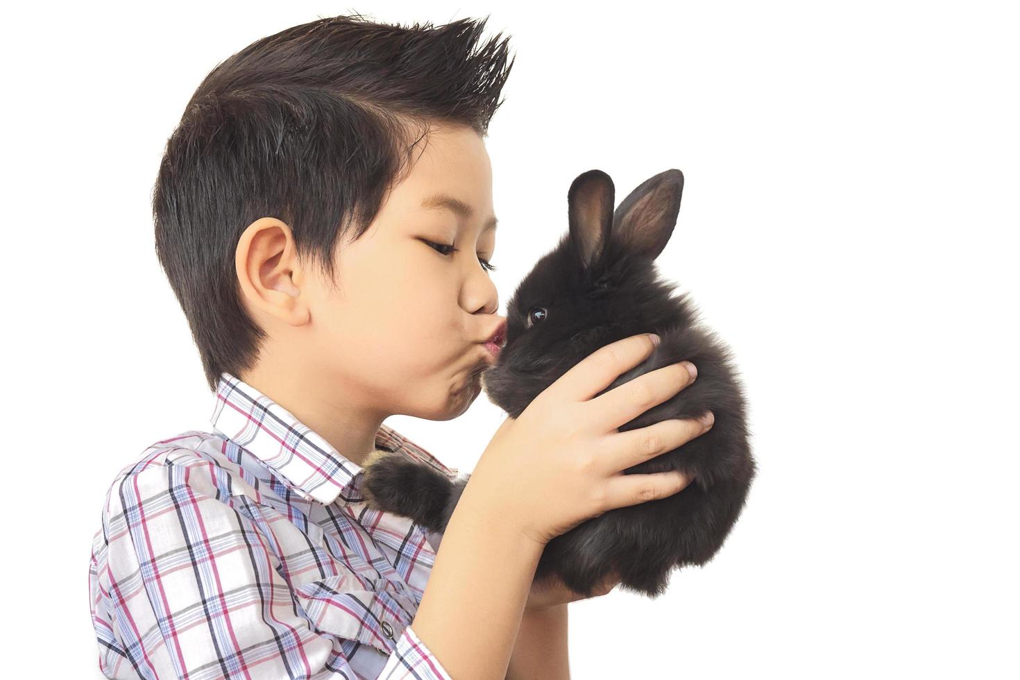 niño asiático jugando con un encantador conejo bebé aislado sobre blanco foto