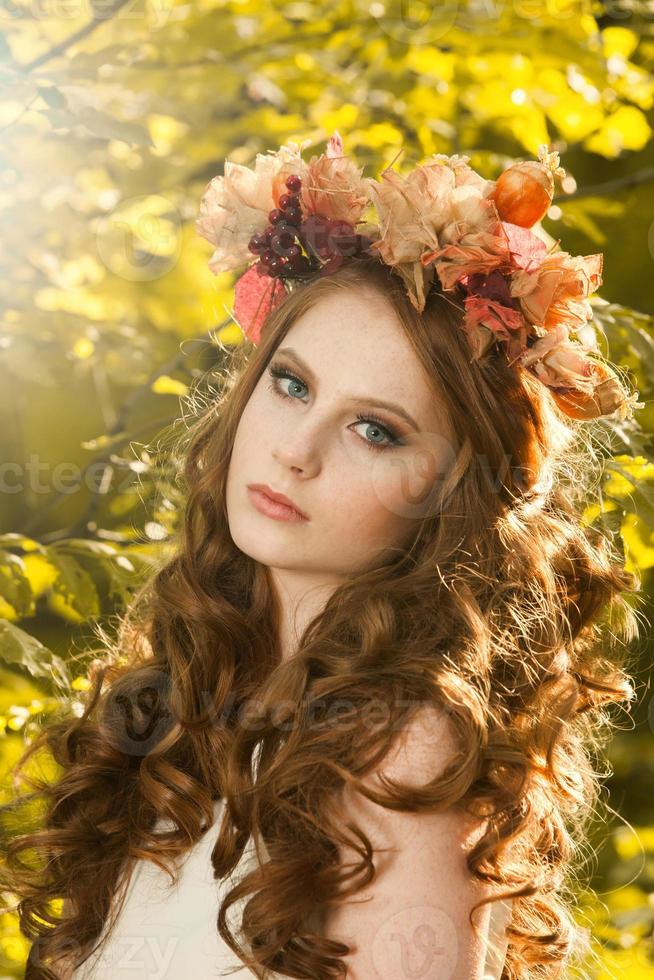 Young woman holding a bunch of yellow maple leaves. Autumn portrait of young woman. Red haired girl in autumn forest photo