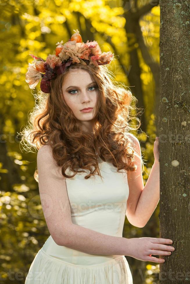 mujer joven sosteniendo un montón de hojas de arce amarillas. retrato de otoño de mujer joven. chica pelirroja en el bosque de otoño foto