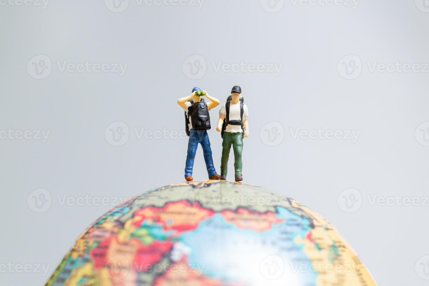 Travelers in miniature, standing on the globe and making their way to their destination, photo