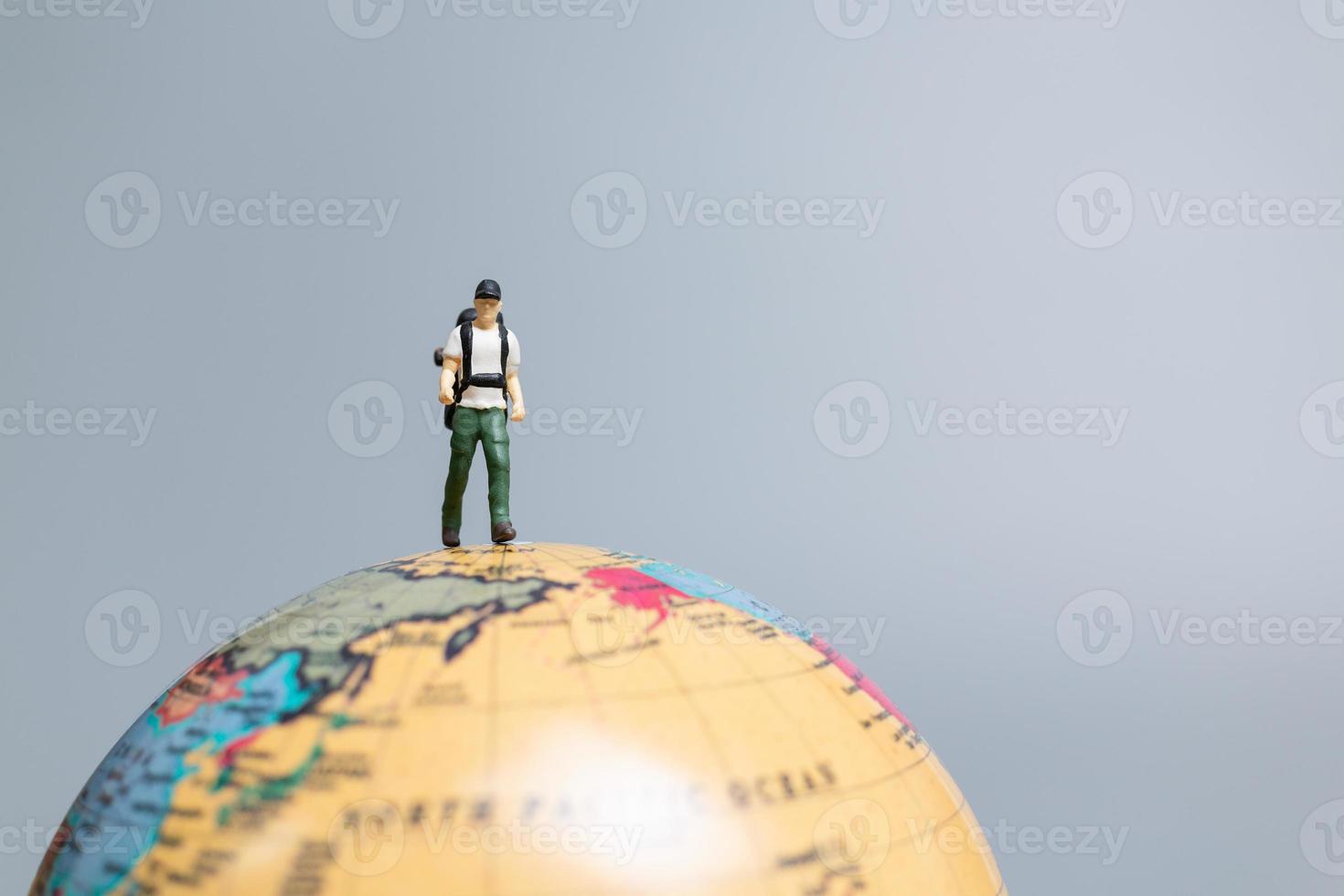 Travelers in miniature, standing on the globe and making their way to their destination, photo